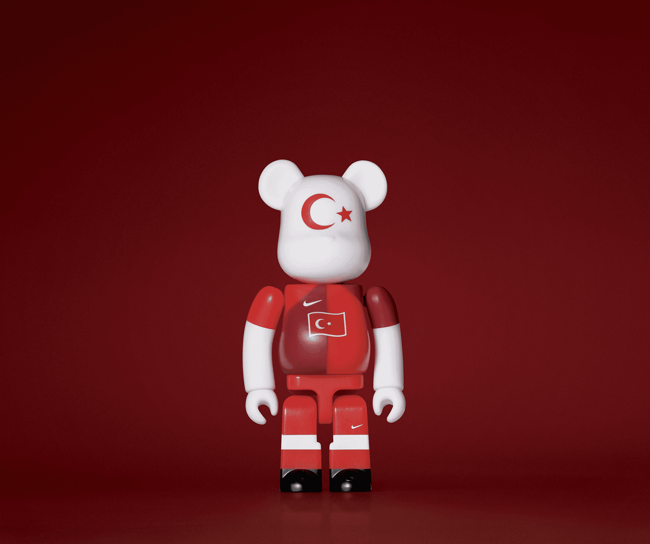 A single 3.5” tall Bre@rbrick/Nike toy created to commemorate the 2006 Turkish World Cup football team. The toy is painted to appear in the Turkish football kit and stands in the center of the frame in front of a dark red background. 