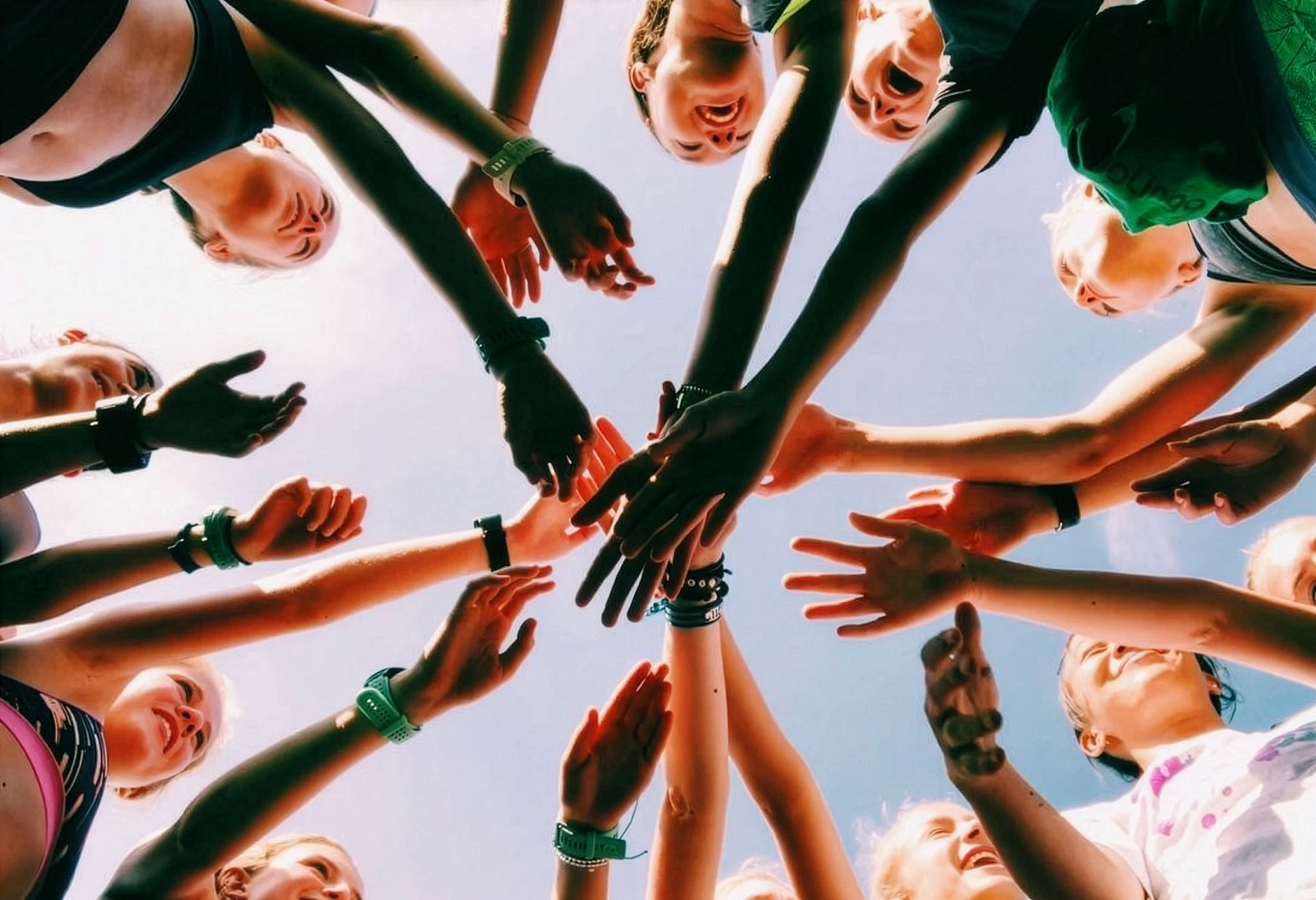 Low-angle view of a team huddling, hands stacked in unity.