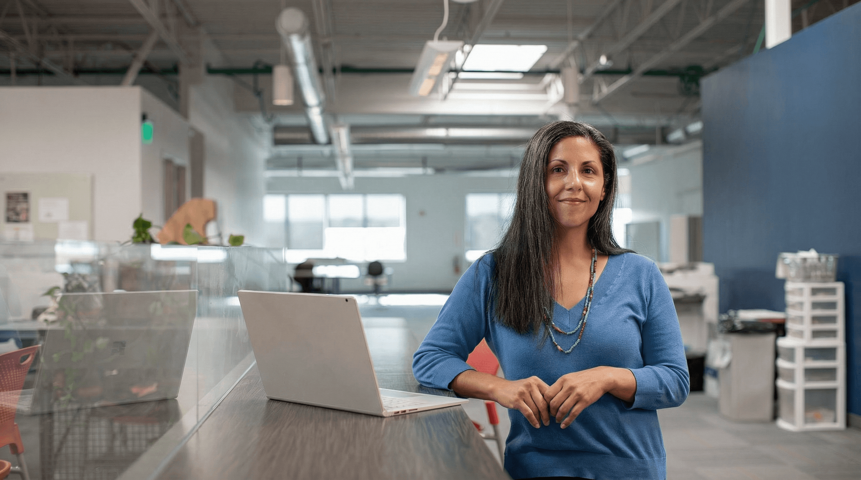 woman in orange long sleeve shirt sitting beside table with macbook pro