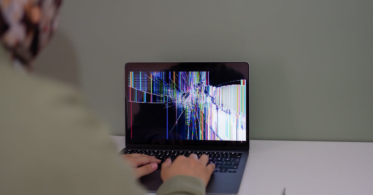 Adult working on a laptop with a cracked screen, indoors setting.
