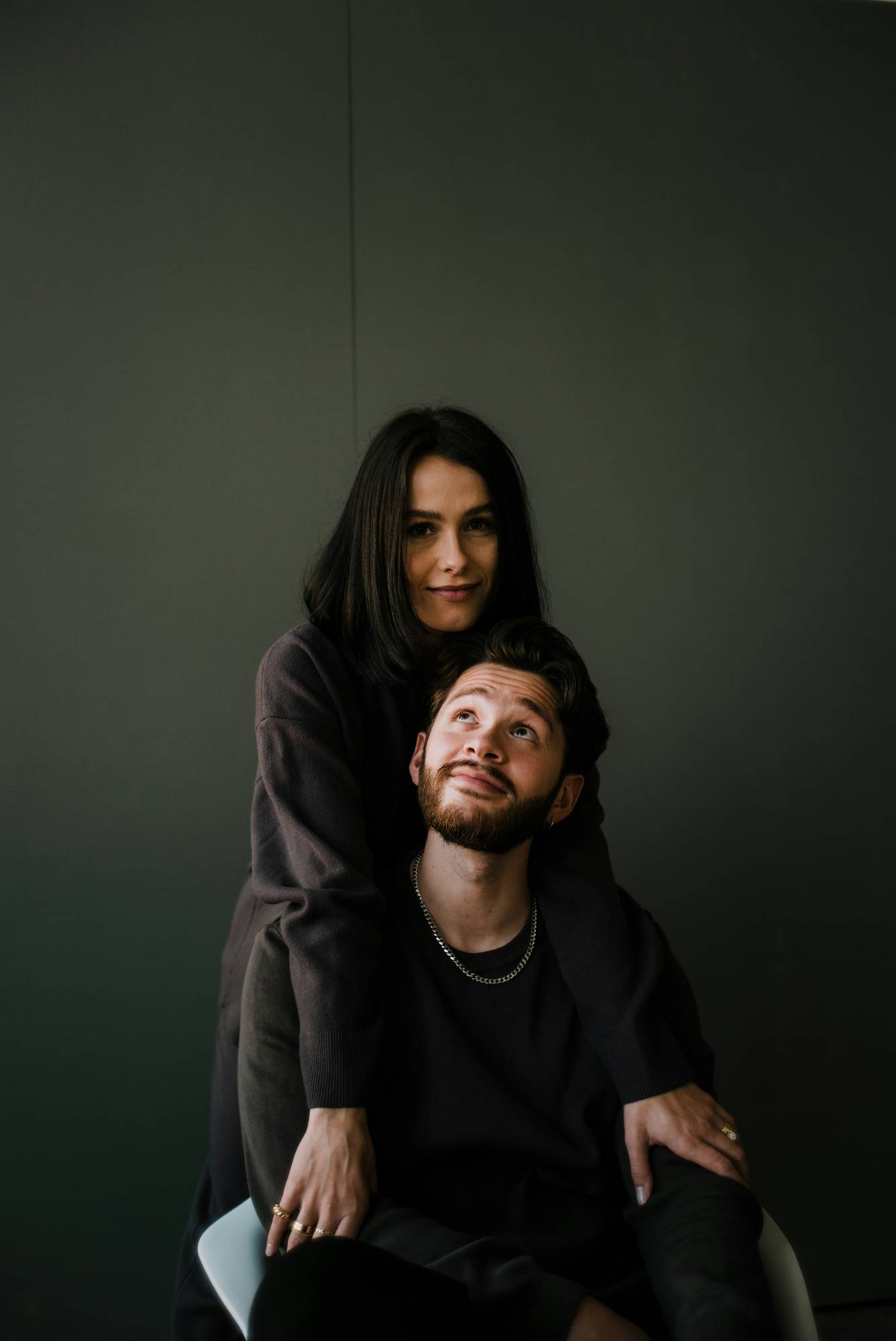 A couple against a dark green studio backdrop
