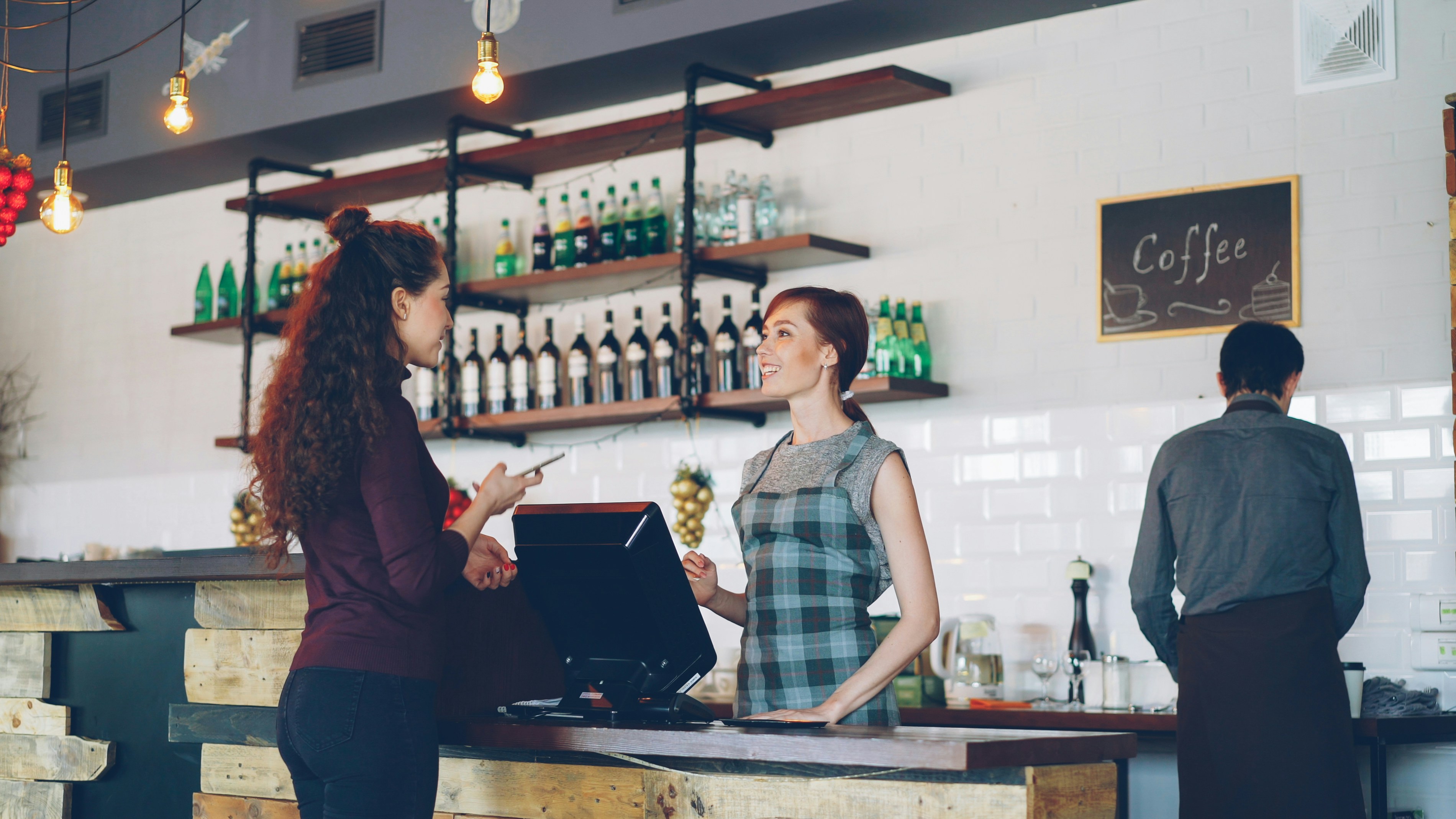 A customer pays at a coffee shop's counter.