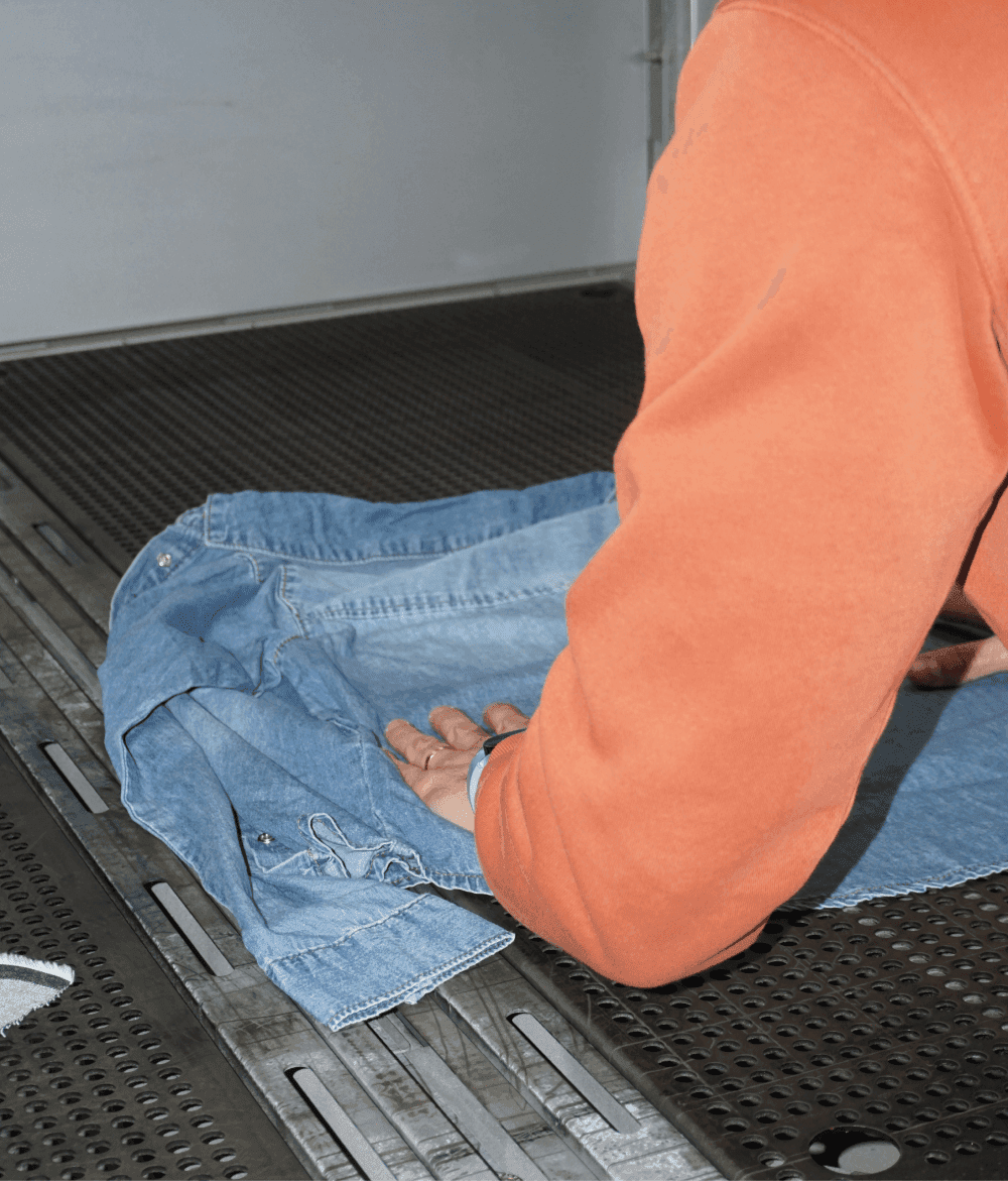 Clothing producer positioning a denim jacket on the table for laser marking