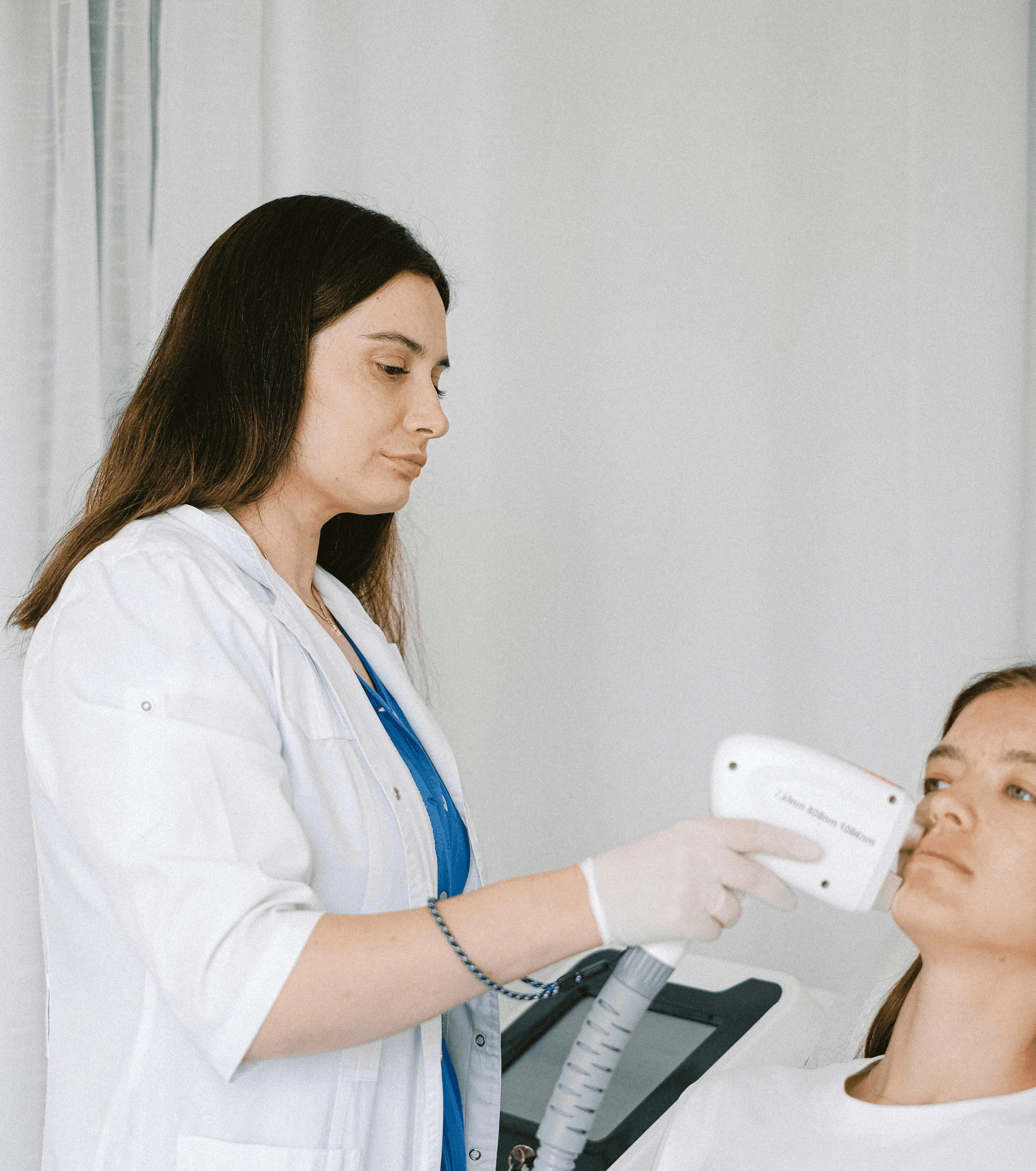 Aesthetician performing HIFU facial treatment using ultrasound device to lift and tighten skin, promoting collagen production for a youthful appearance.
