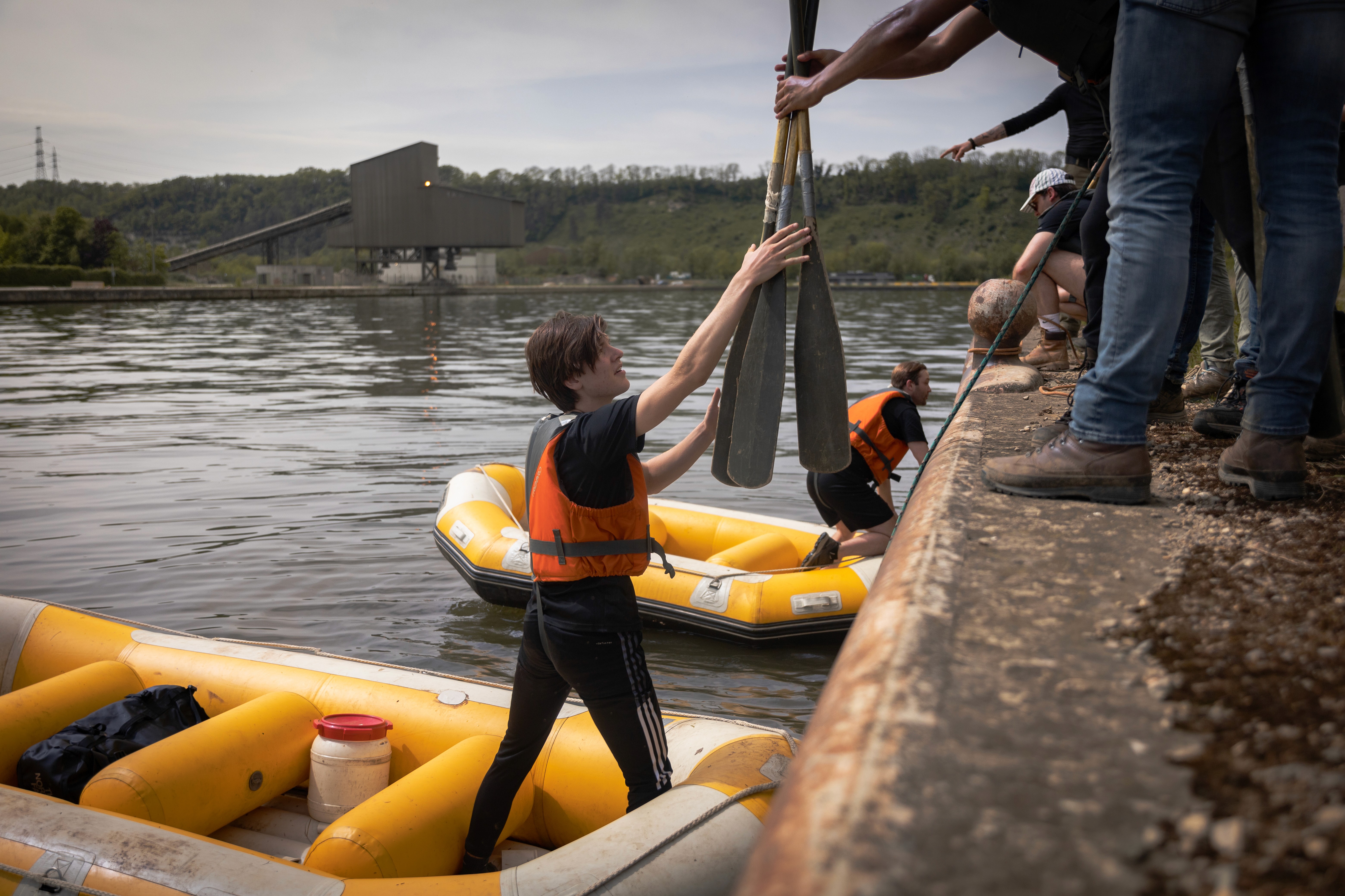 Smiling young man with short hair poses against a dark background, wearing a green button-up shirt.