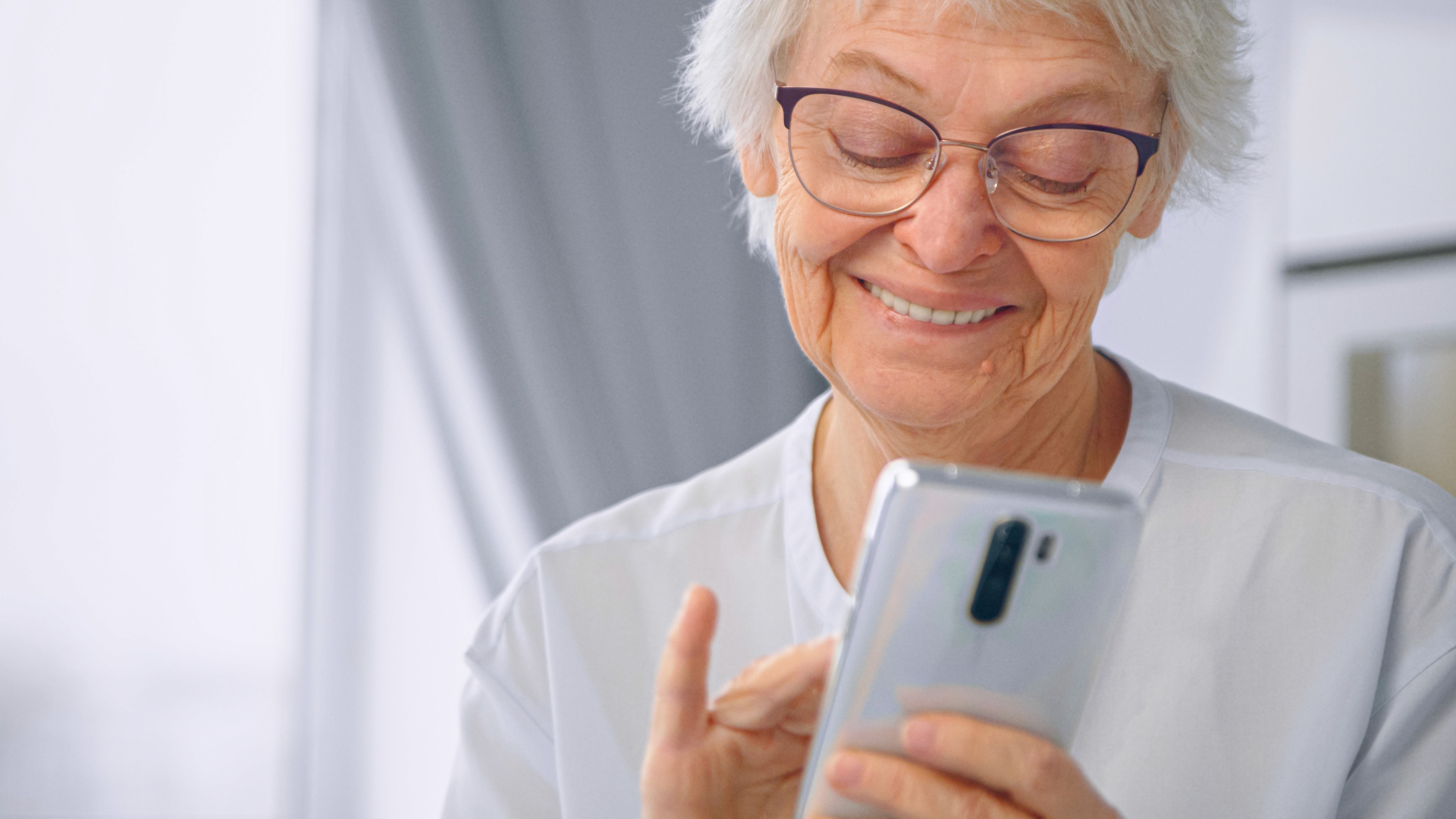 Older adult using a smartphone to access Medicaid member services and healthcare benefits on a mobile-first platform.