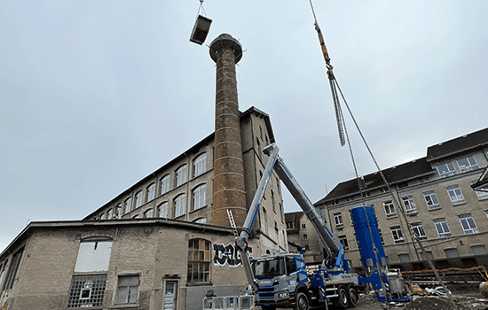 Four diverse professionals collaboratively working on a laptop, with one person pointing at the screen while others observe.