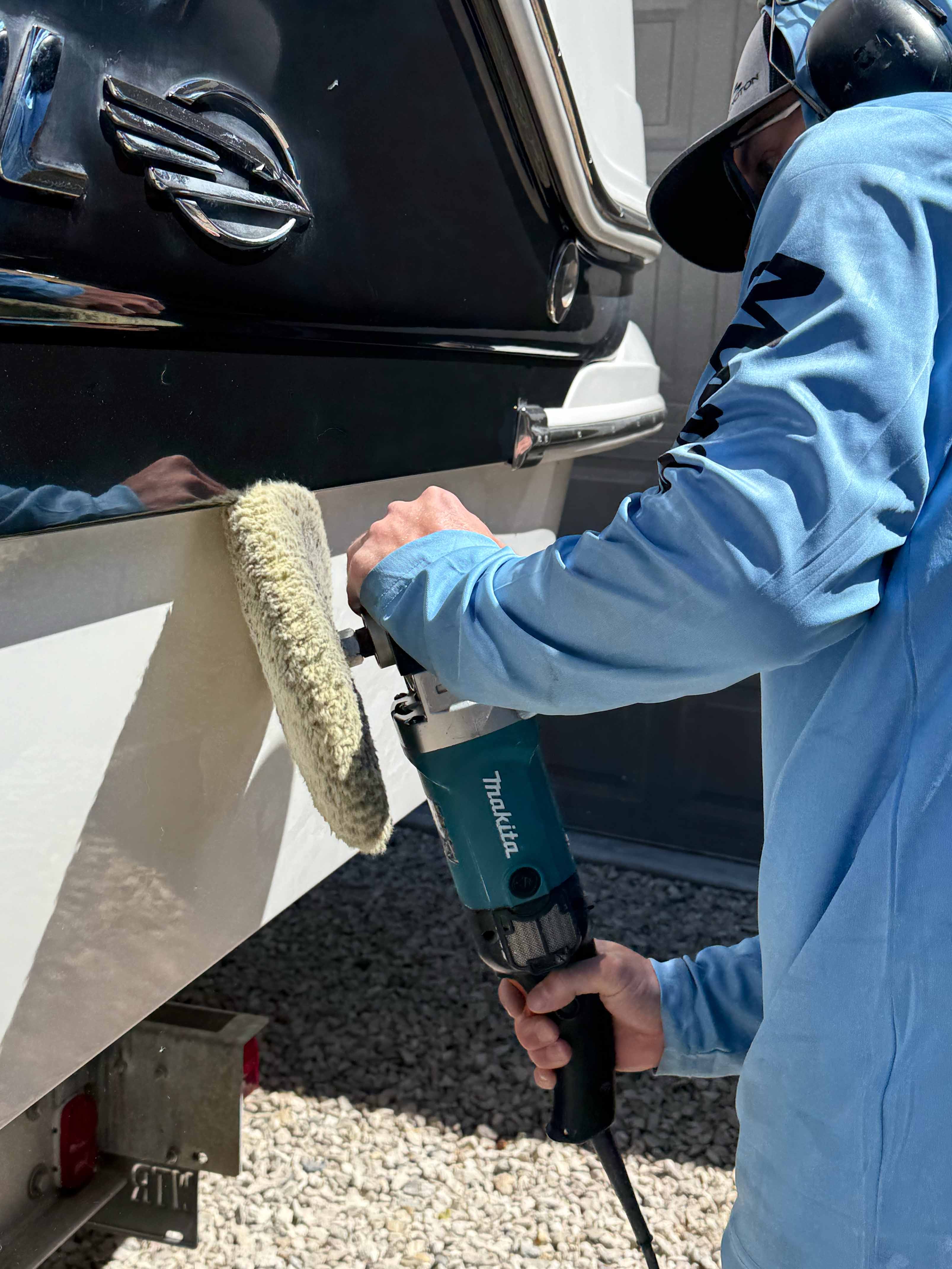 A man buffing out and polishing the side of a boat. The man is doing a heavy cut and polish detail.