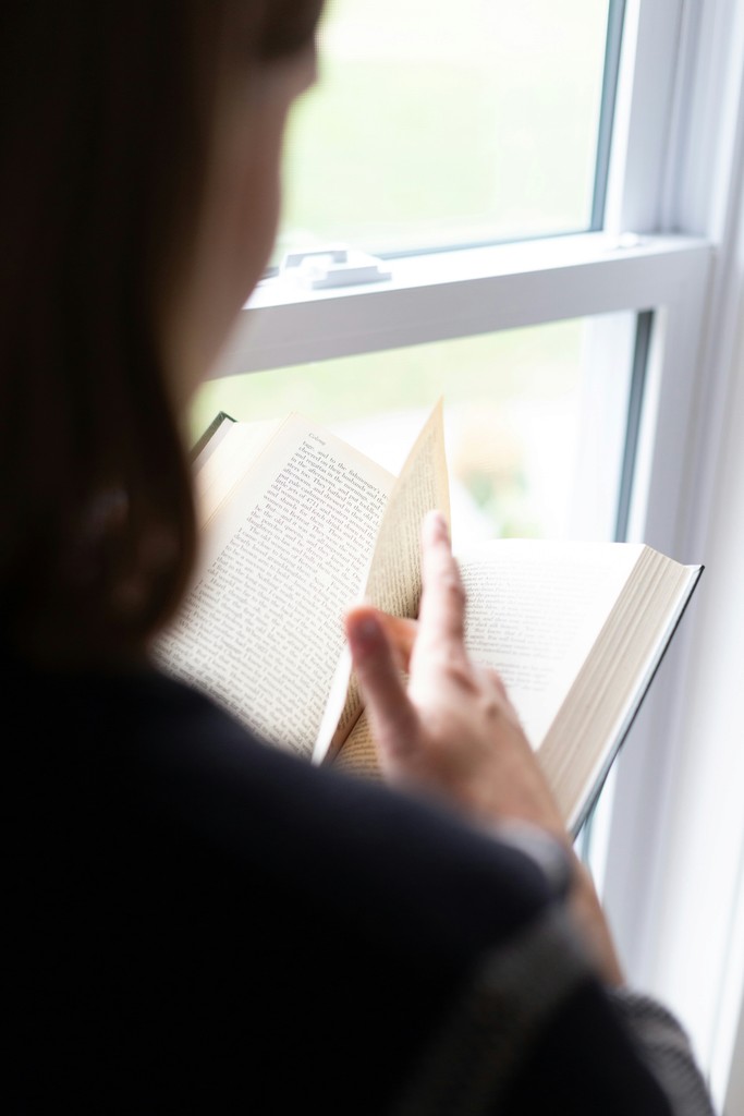 A woman reading a book by a window