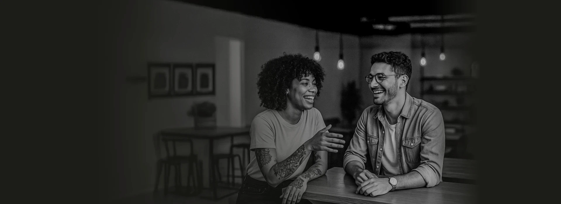 Casal de empreendedores em ambiente moderno e acolhedor, sorrindo em momento de colaboração.