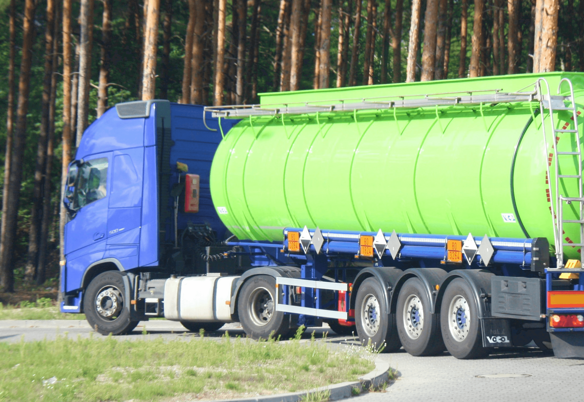 a large green tanker truck driving down a road