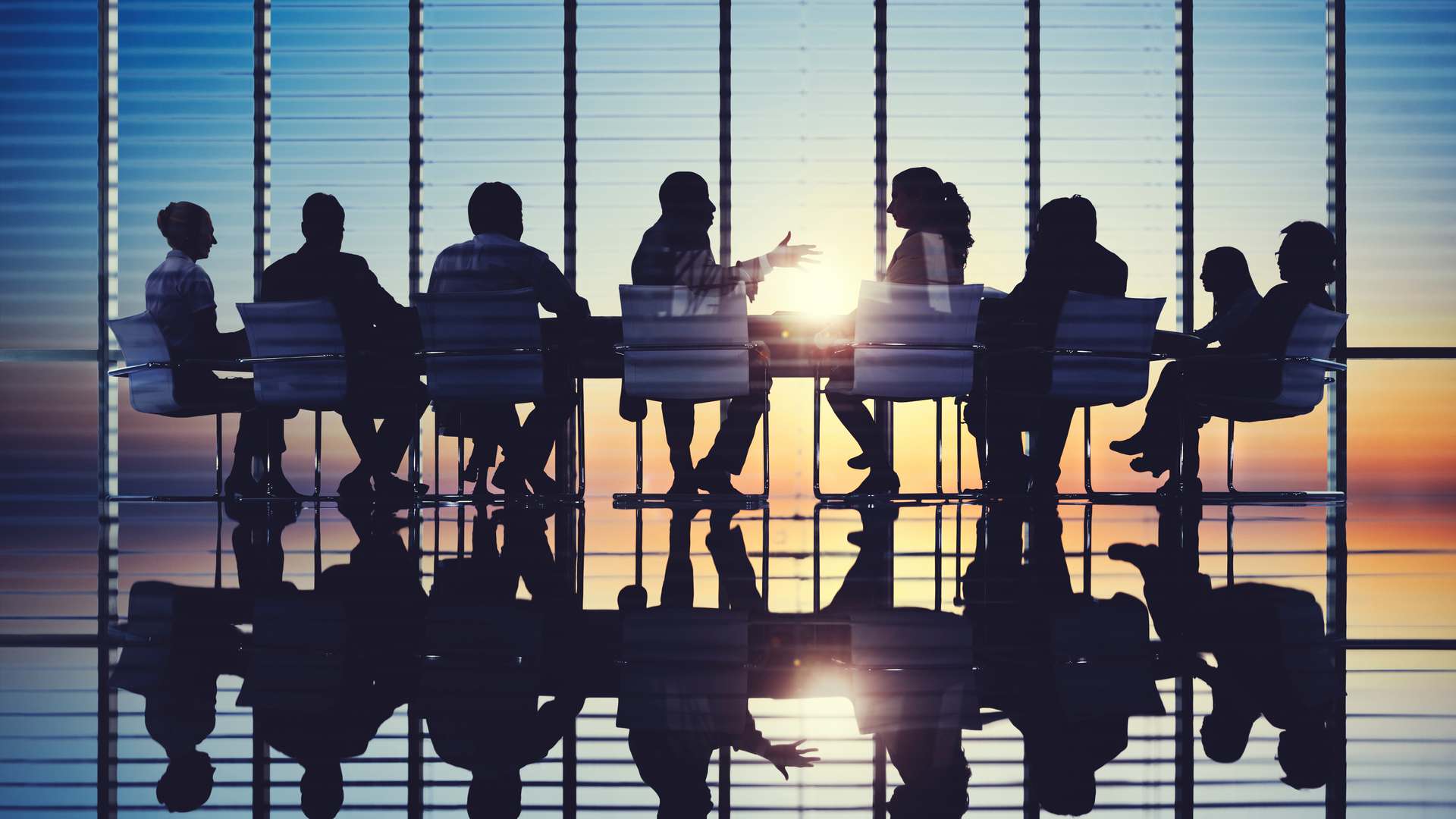 A stock image of a sillouhette of people in a meeting room.