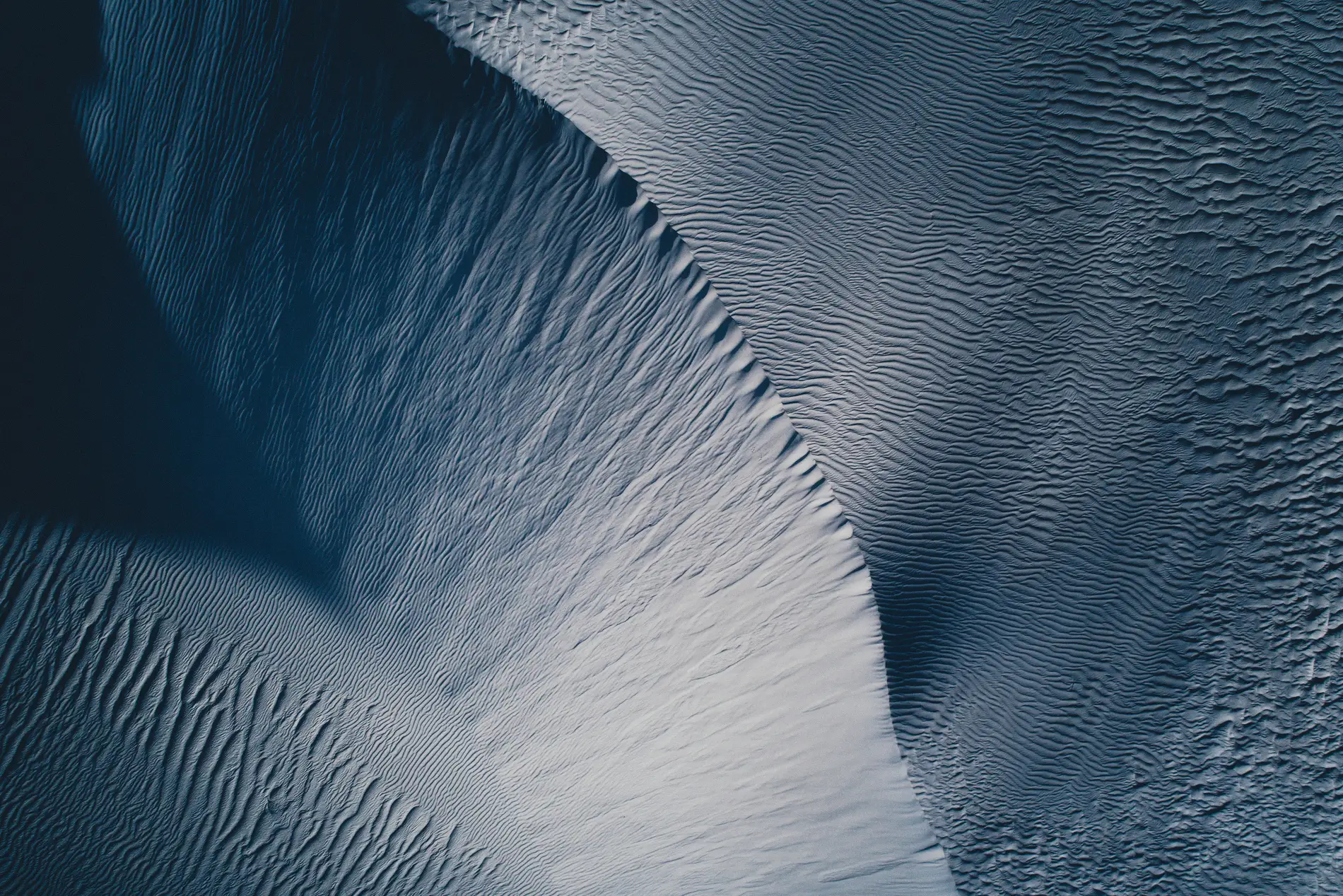 Aerial looking down on wind-rippled white sand dunes