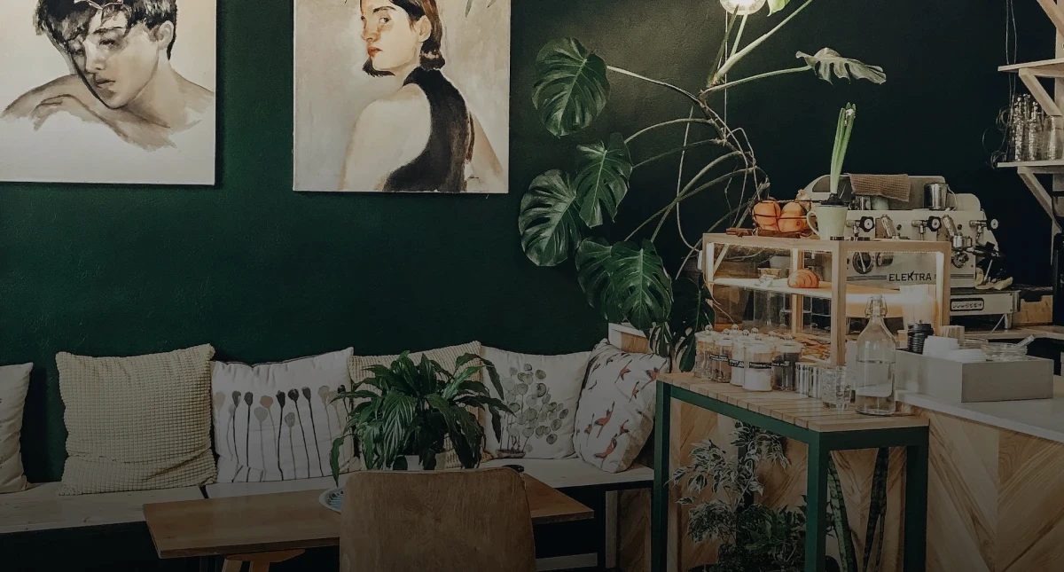 imagem de um espaço comercial projetado com elegância. O espaço foi projetado tendo a presença de elementos naturais como plantas e flores. O ambiente tem cores que remetem a natureza, como o verde e o marrom amadeirado.