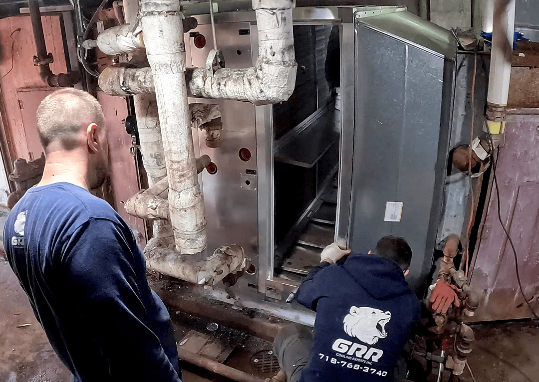 GRR technicians performing a live hospital HVAC retrofit inside a mechanical room, replacing aging chilled water coil equipment.