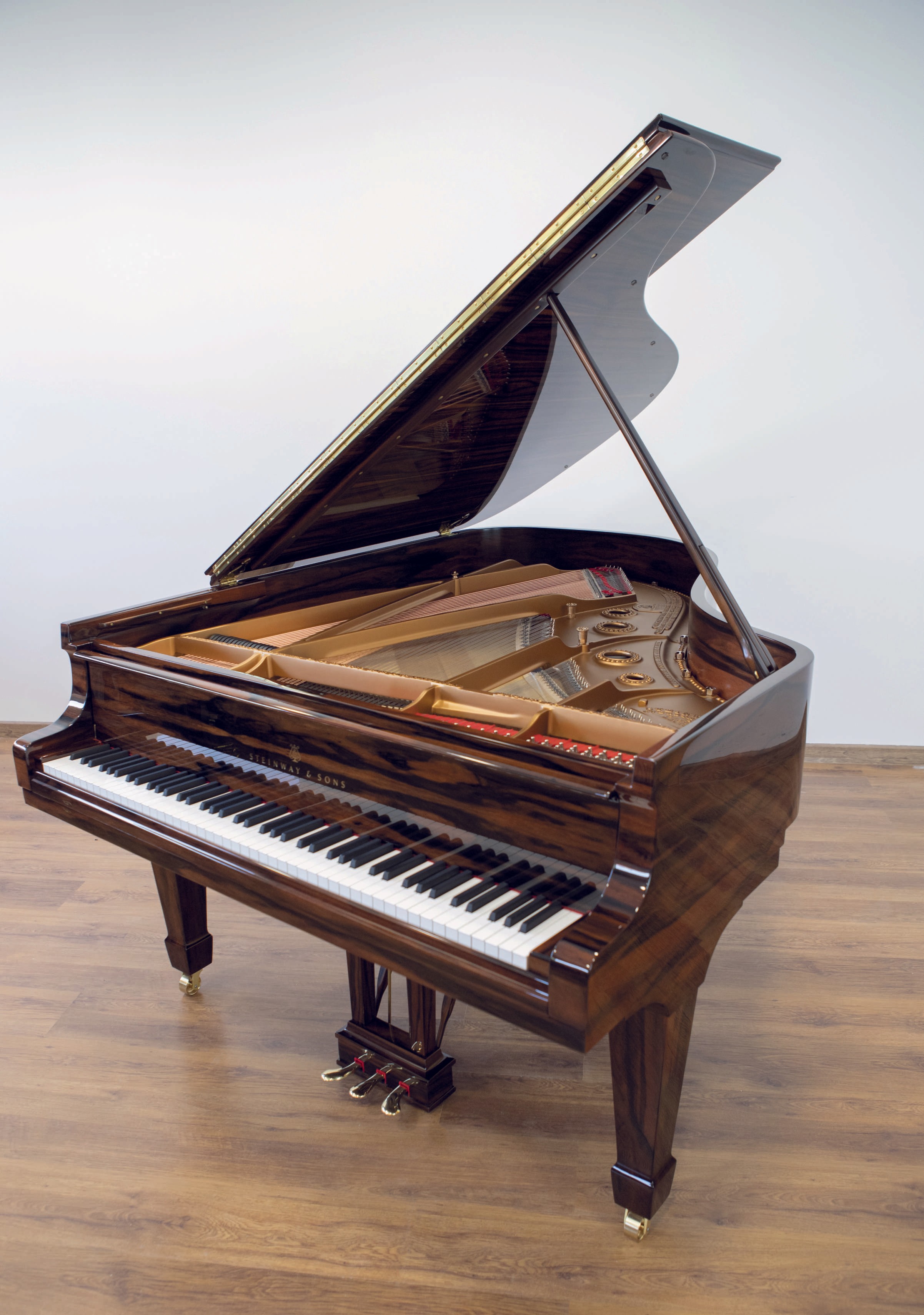 A fully restored Steinway & Sons grand piano standing in a bright room. The polished Macassar veneer enhances its luxurious appearance.