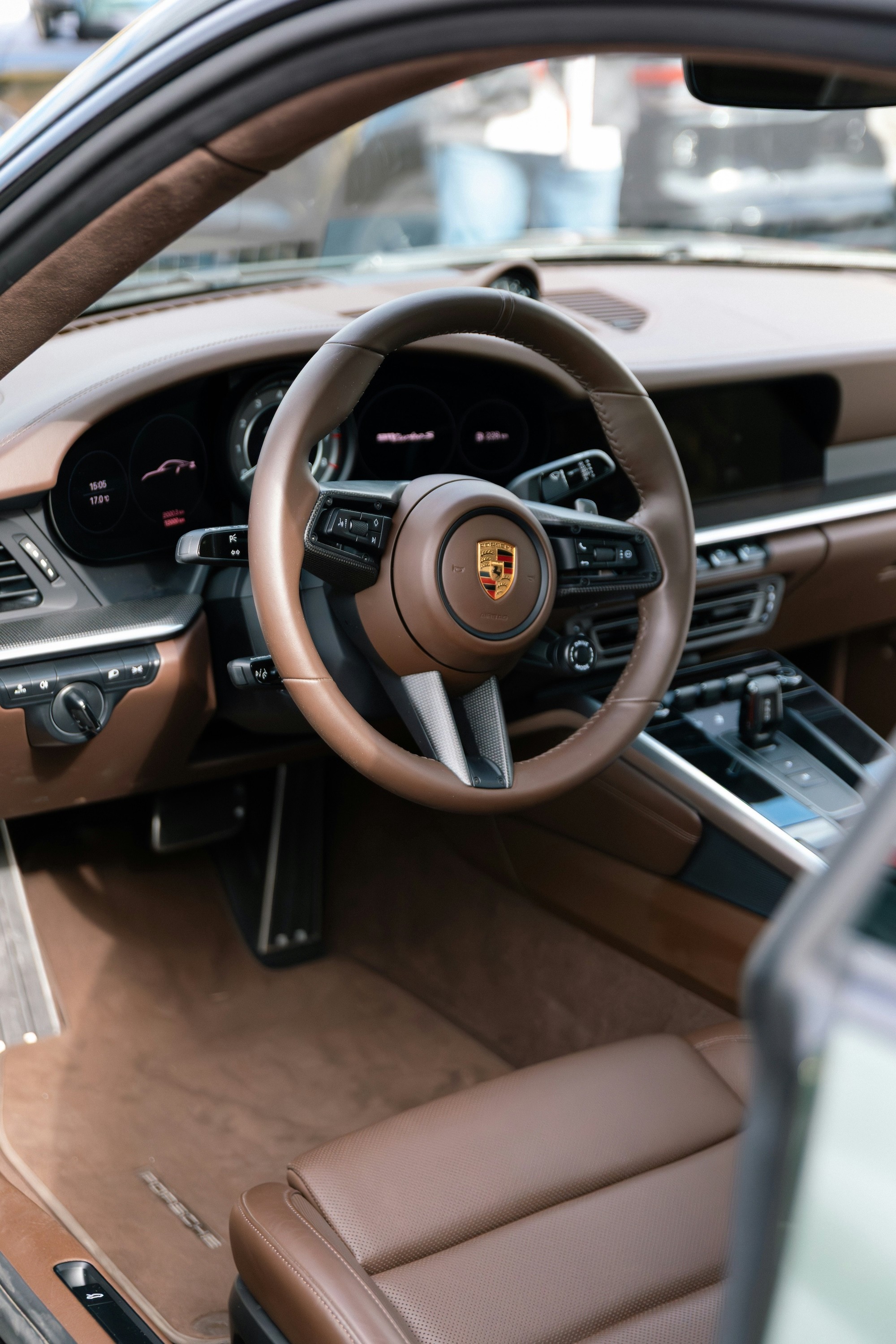The interior of a luxurious car showcasing a brown leather steering wheel and dashboard, featuring modern control panels and digital displays.