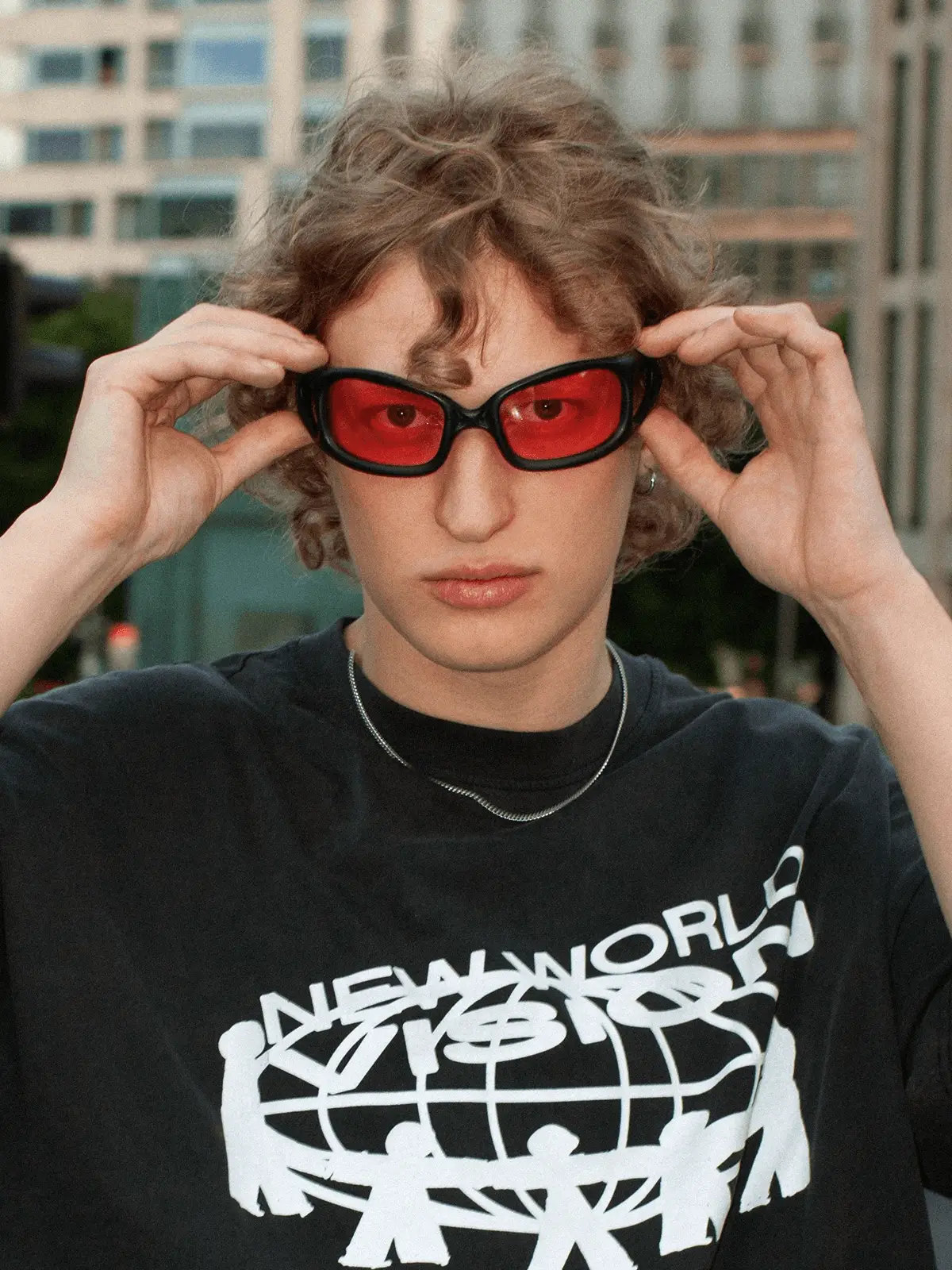Model setzt orange verpsiegelte Brille auf und schaut in die Kamera