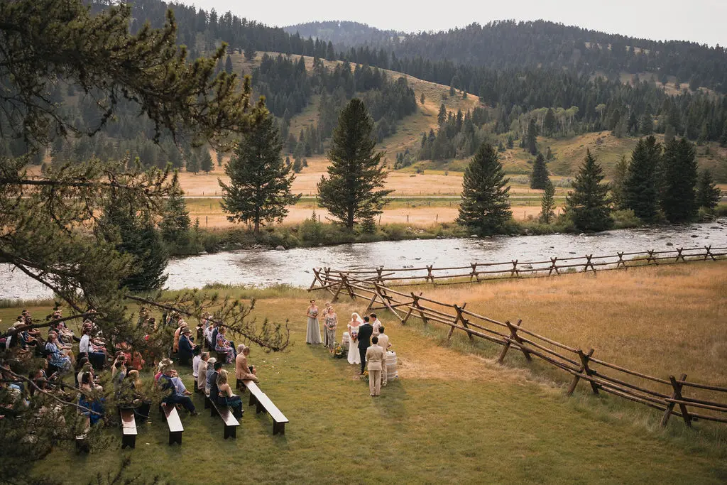 Outdoor wedding ceremony beside a river in a mountain valley
