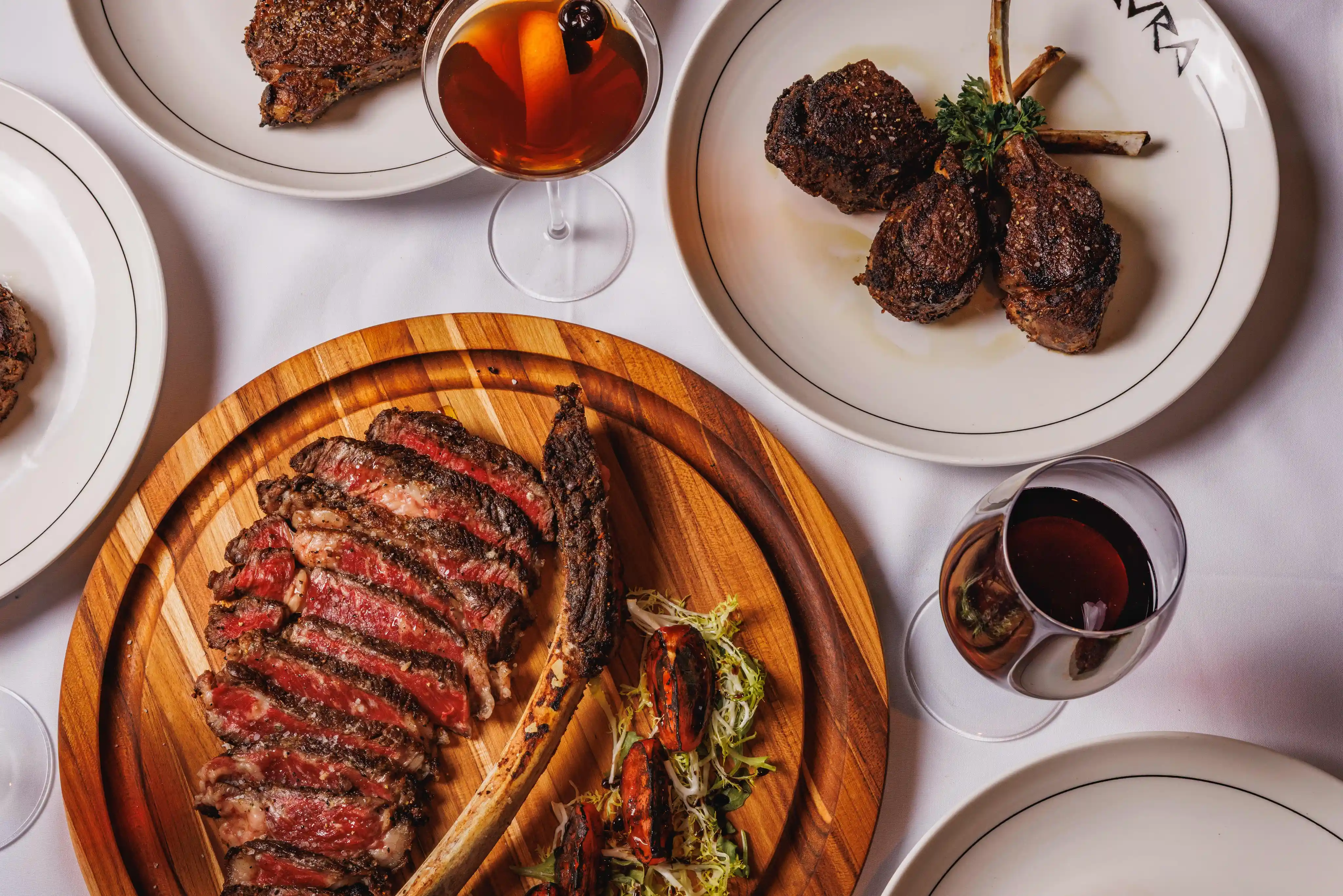 A stylish restaurant interior with a wooden ceiling, hanging plants, and a bright bar area.