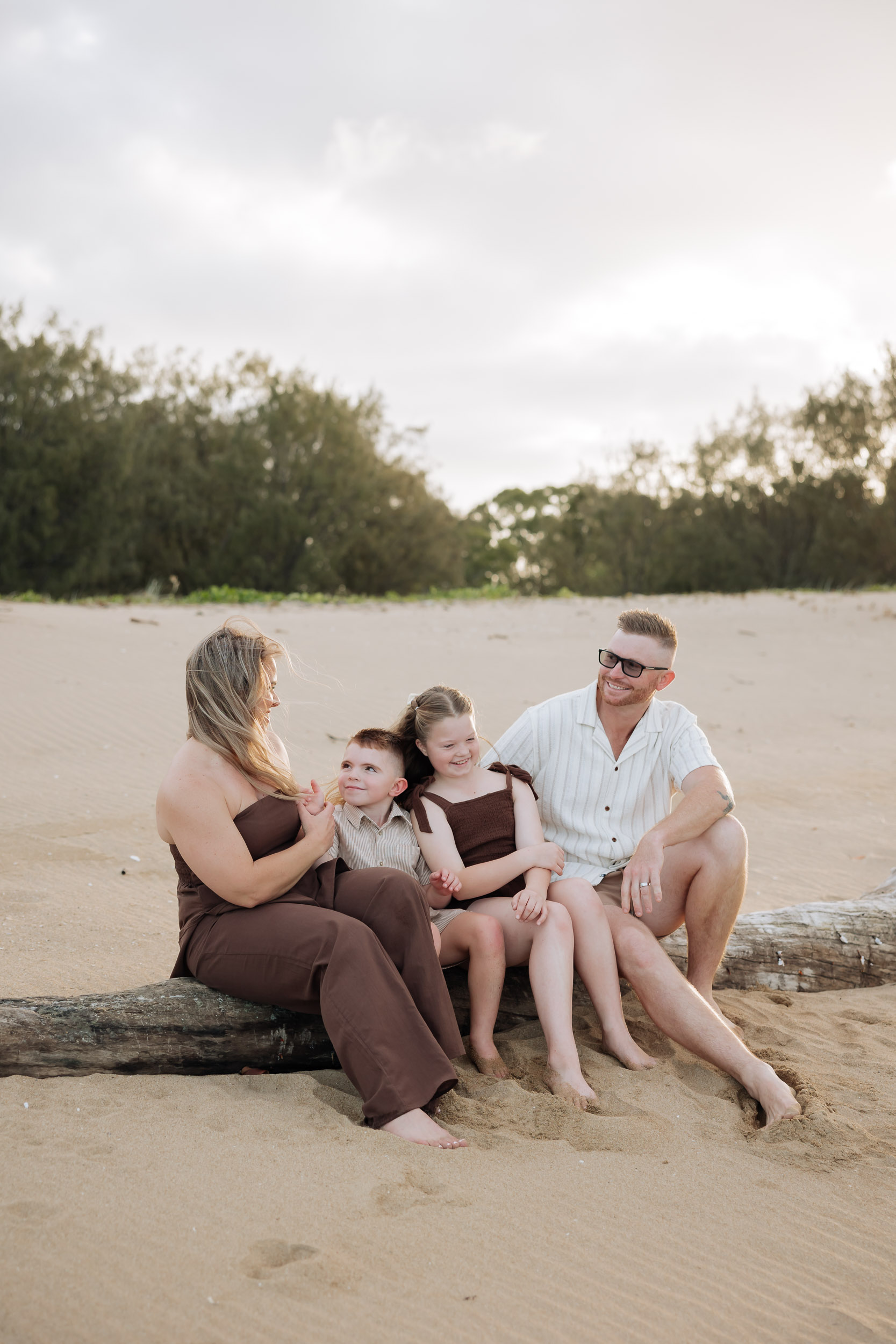 Young family laughing together during a natural lifestyle family photography session at the beach in Mackay