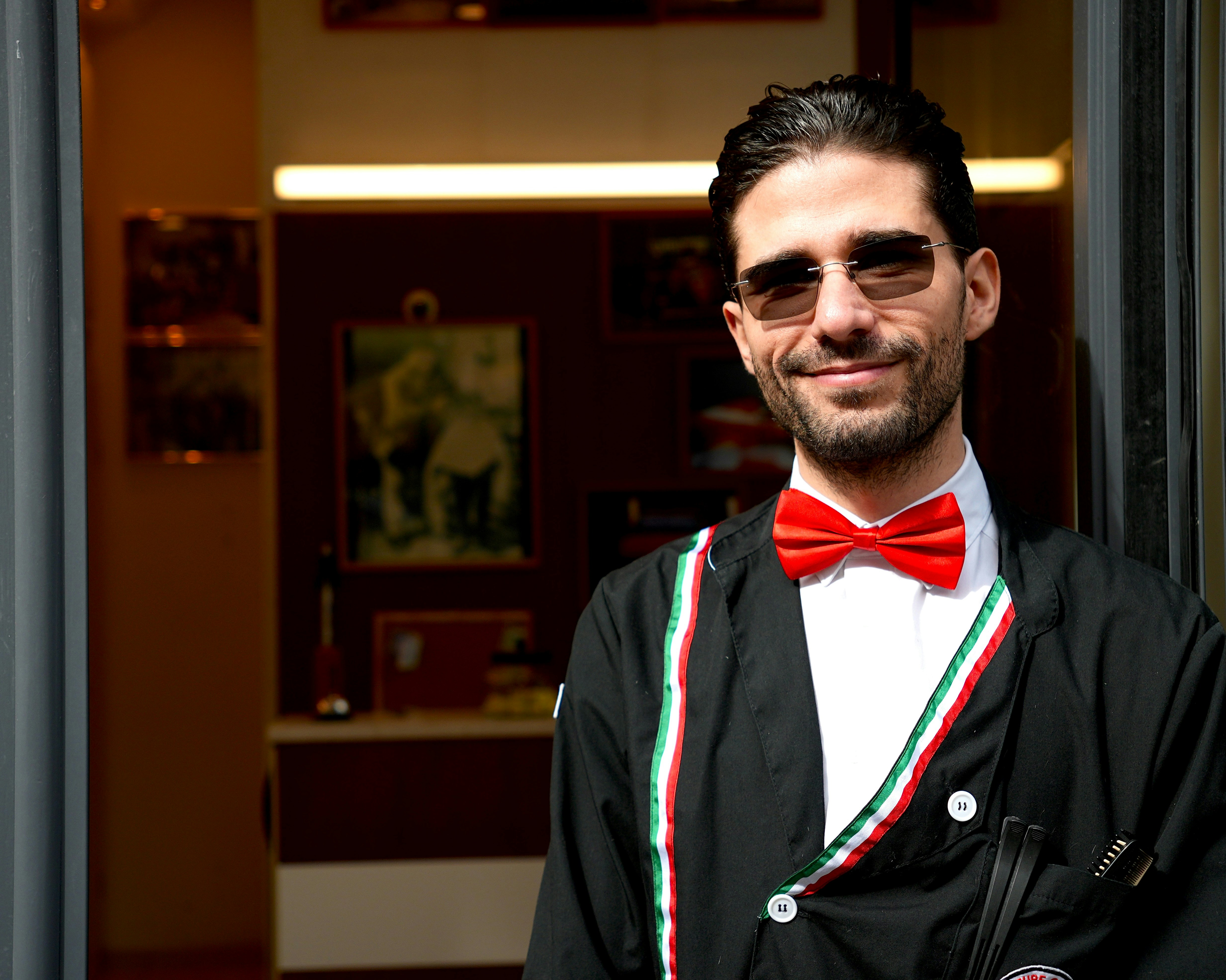 Man in sunglasses wearing a red bowtie and jacket.