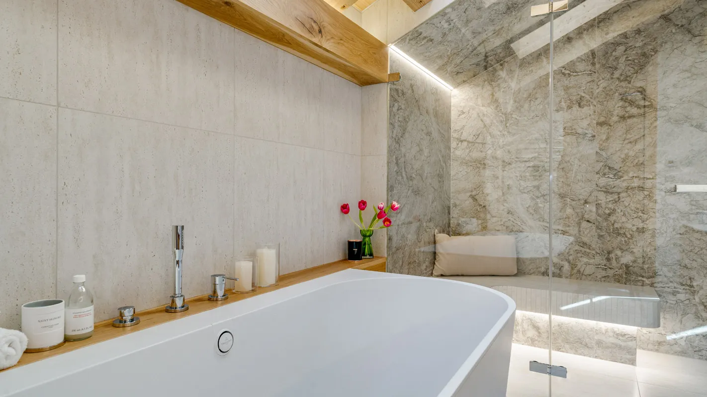Silvretta Klosters bathroom with a freestanding bathtub, glass shower, and marble-effect wall finishes