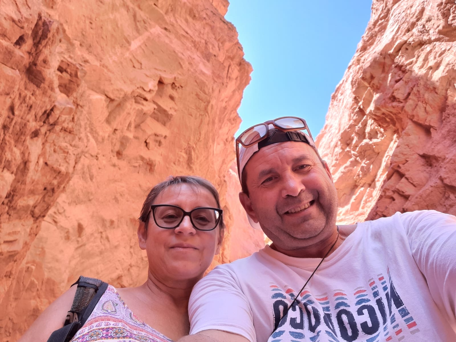 Mujer sentada sobre un tronco frente a una cascada doble en un bosque frondoso de Argentina.