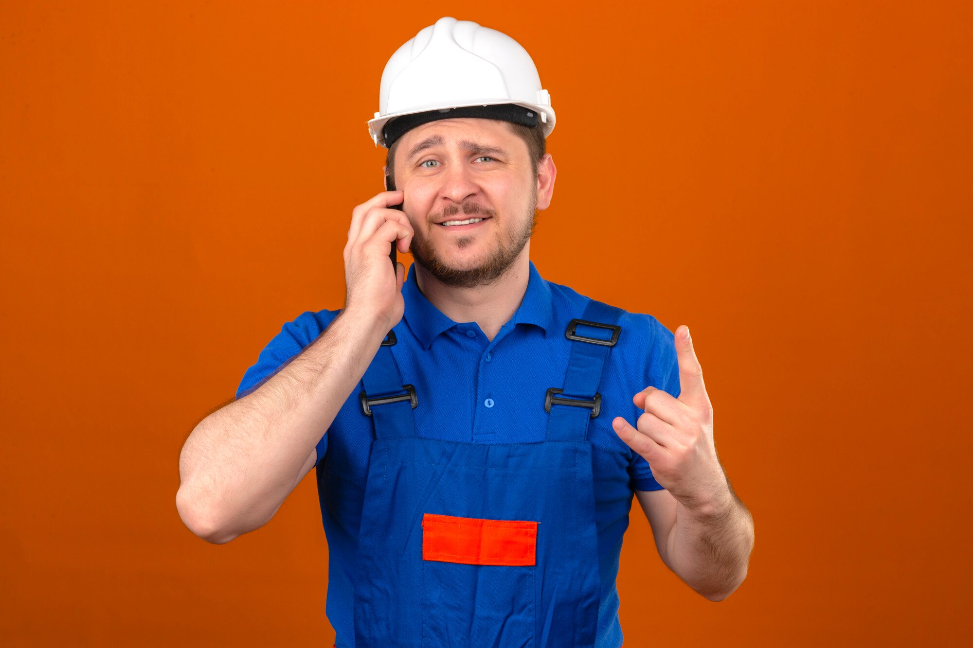 Monteur in veiligheidshelm bespreekt klantverzoek via telefoon