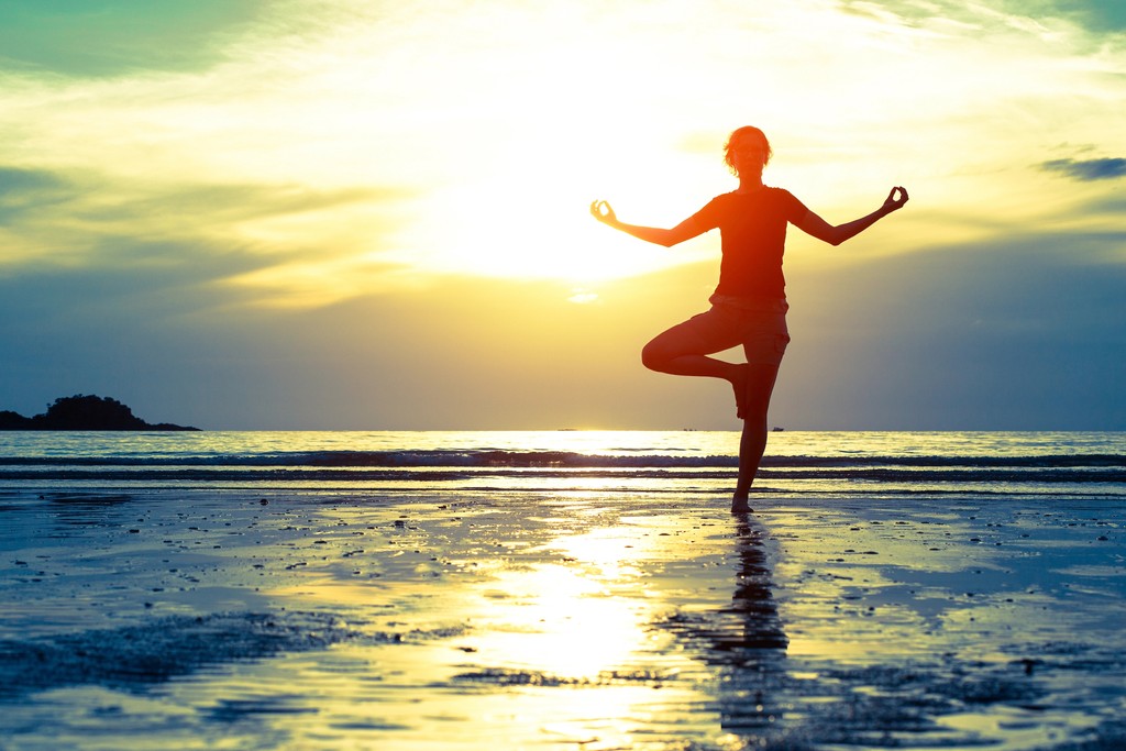 Woman practicing yoga at the beach