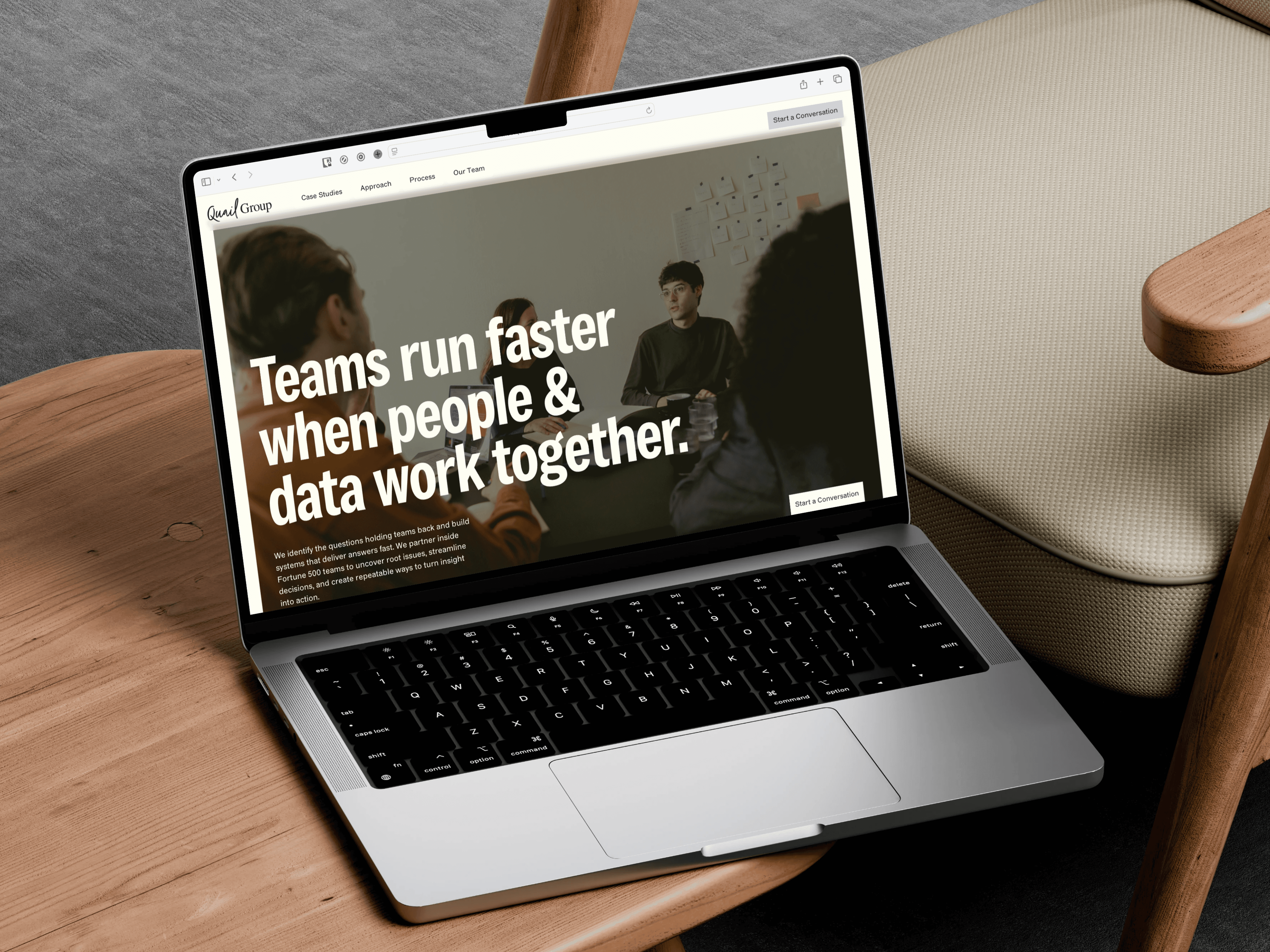 Mockup of Quail Group landing page on laptop, which is placed on top of wooden table