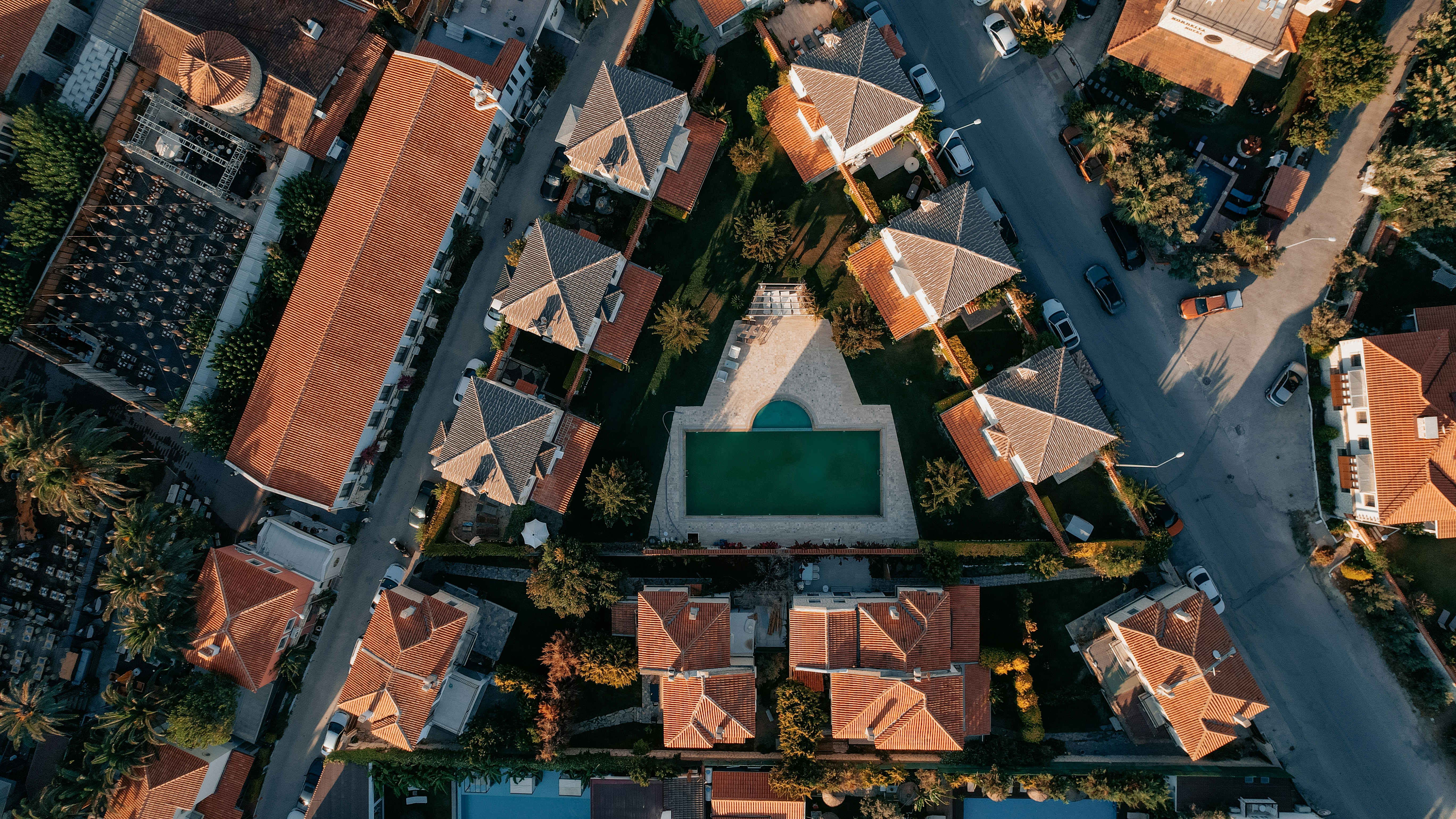 Aerial view of a residential neighborhood with houses, trees, and a central swimming pool.