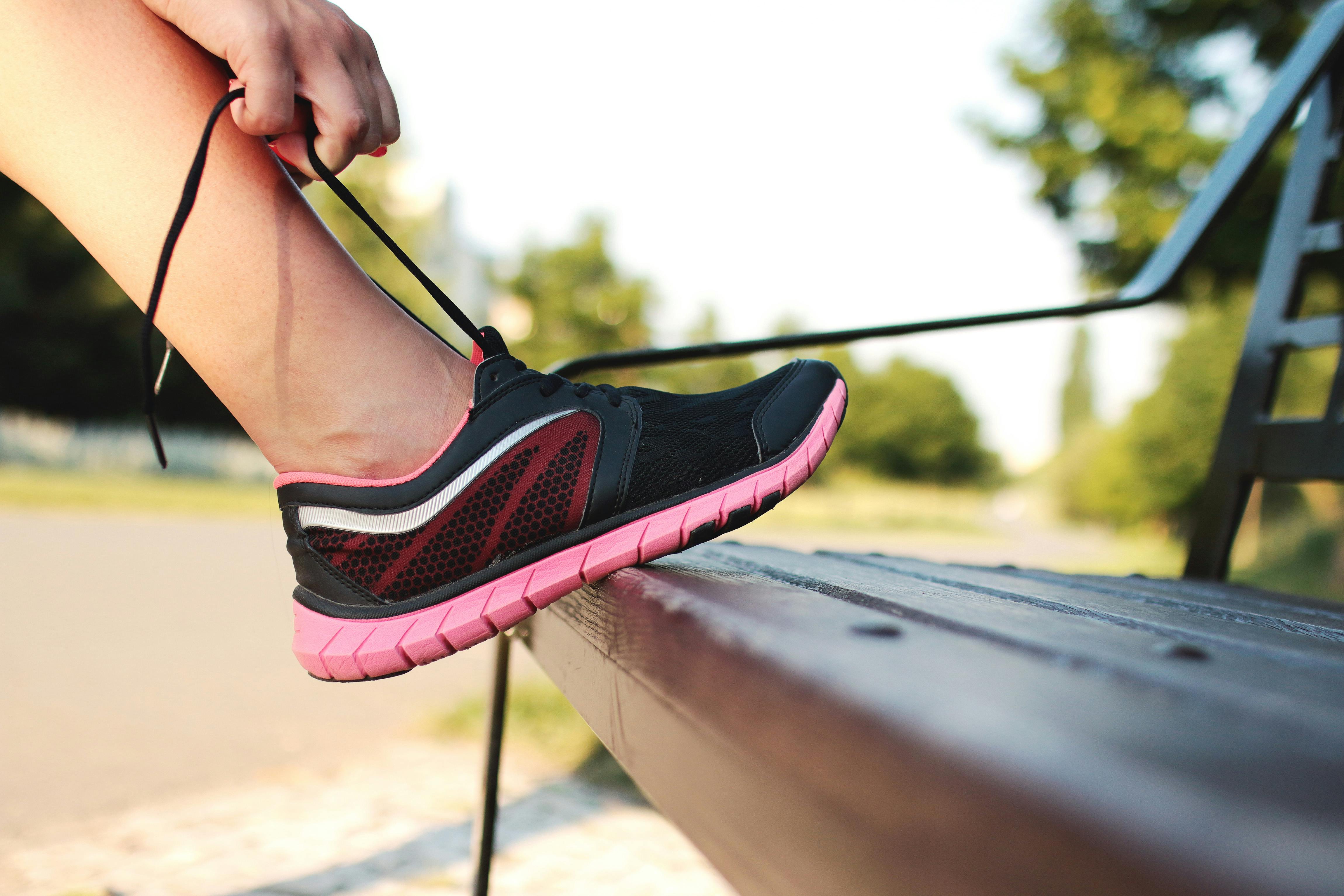 A runner laces up their running shoes on a bench