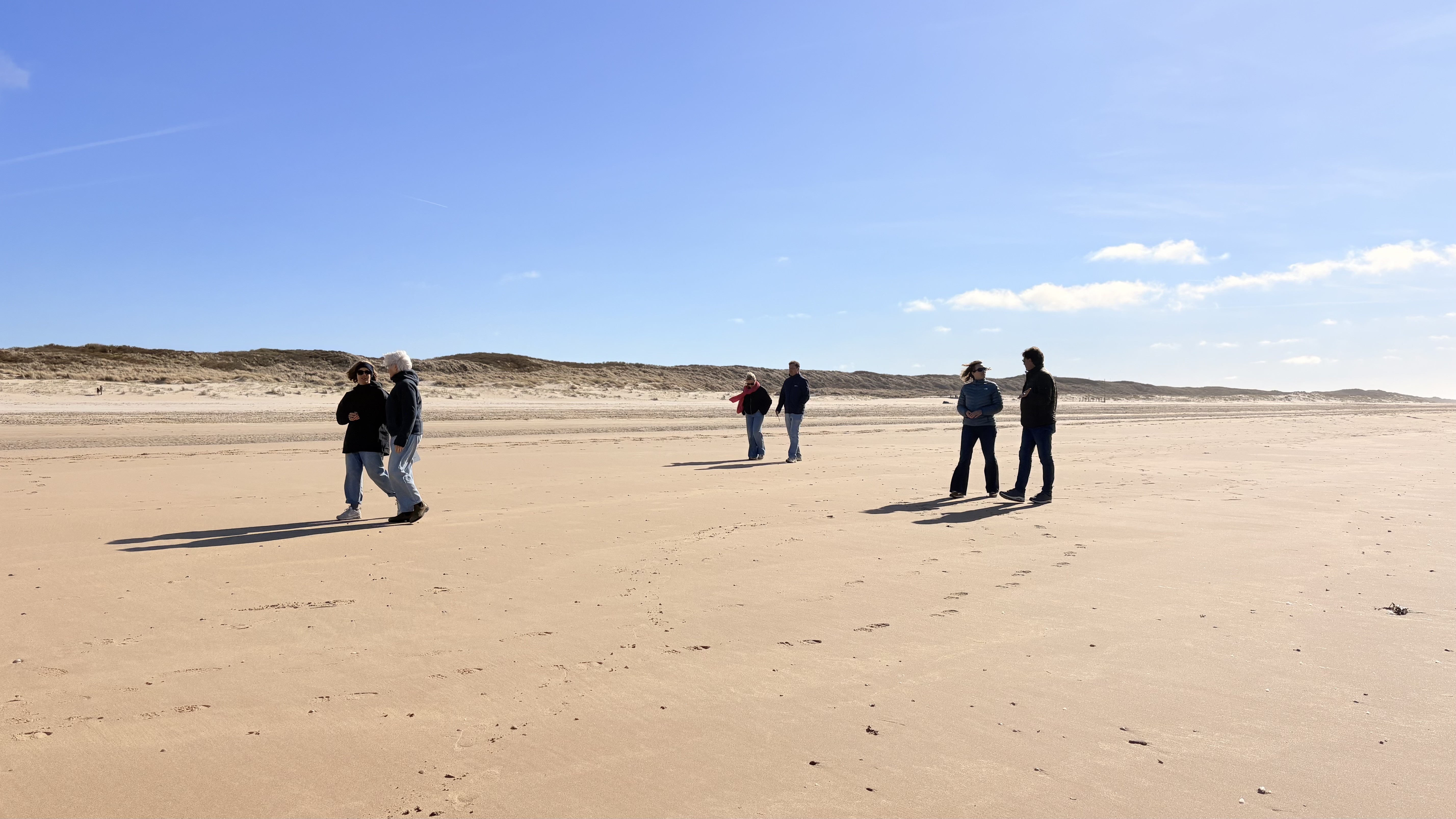 Leadership team on a carousel walk along the beach, talking in pairs