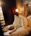 Woman laying in bed in The Companion Hotel, laughing.