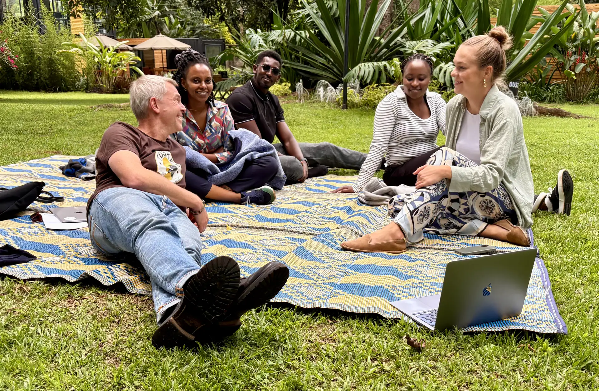 Group of Impacc team members laying on the grass and smiling