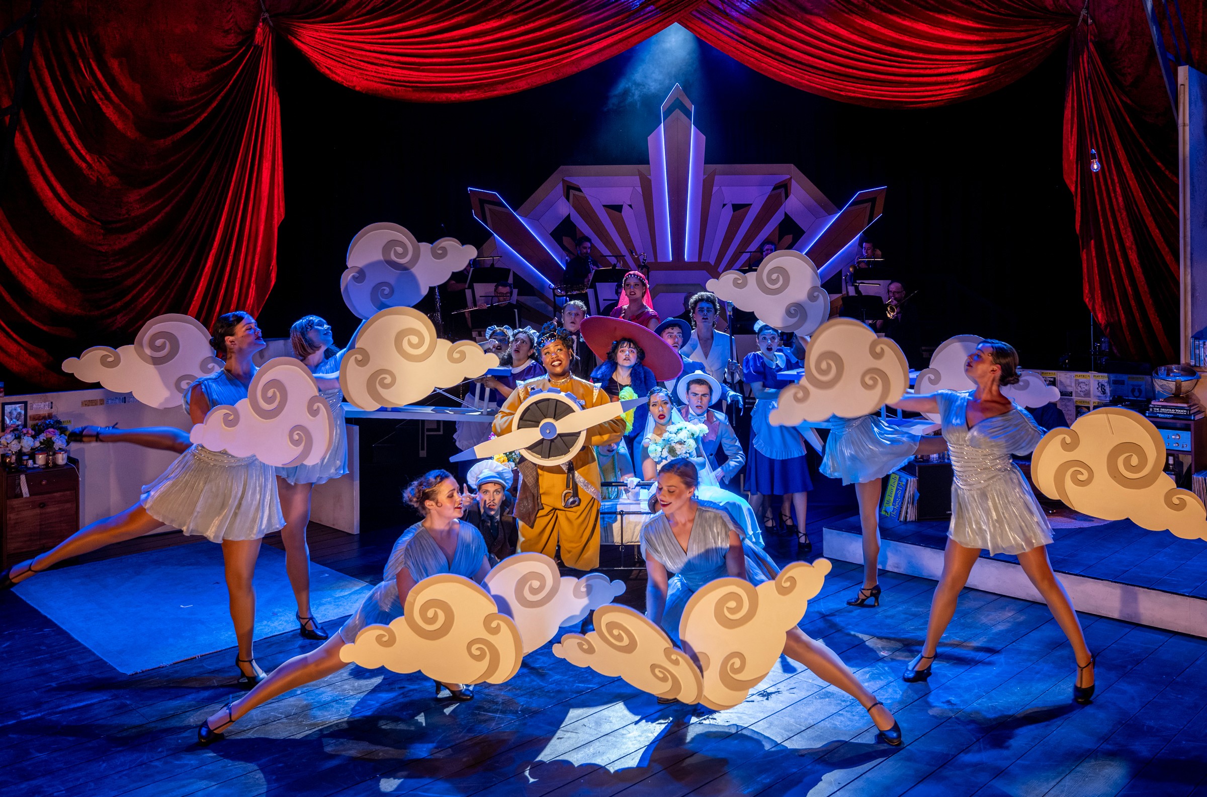 Trix, The Aviatrix surrounded by cloud dancers in a makeshift cardboard plane