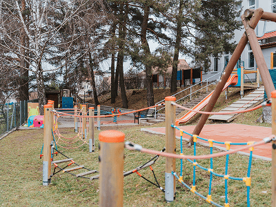 Venkovní dětské hřiště s lanovými prolézačkami v přírodním areálu školky