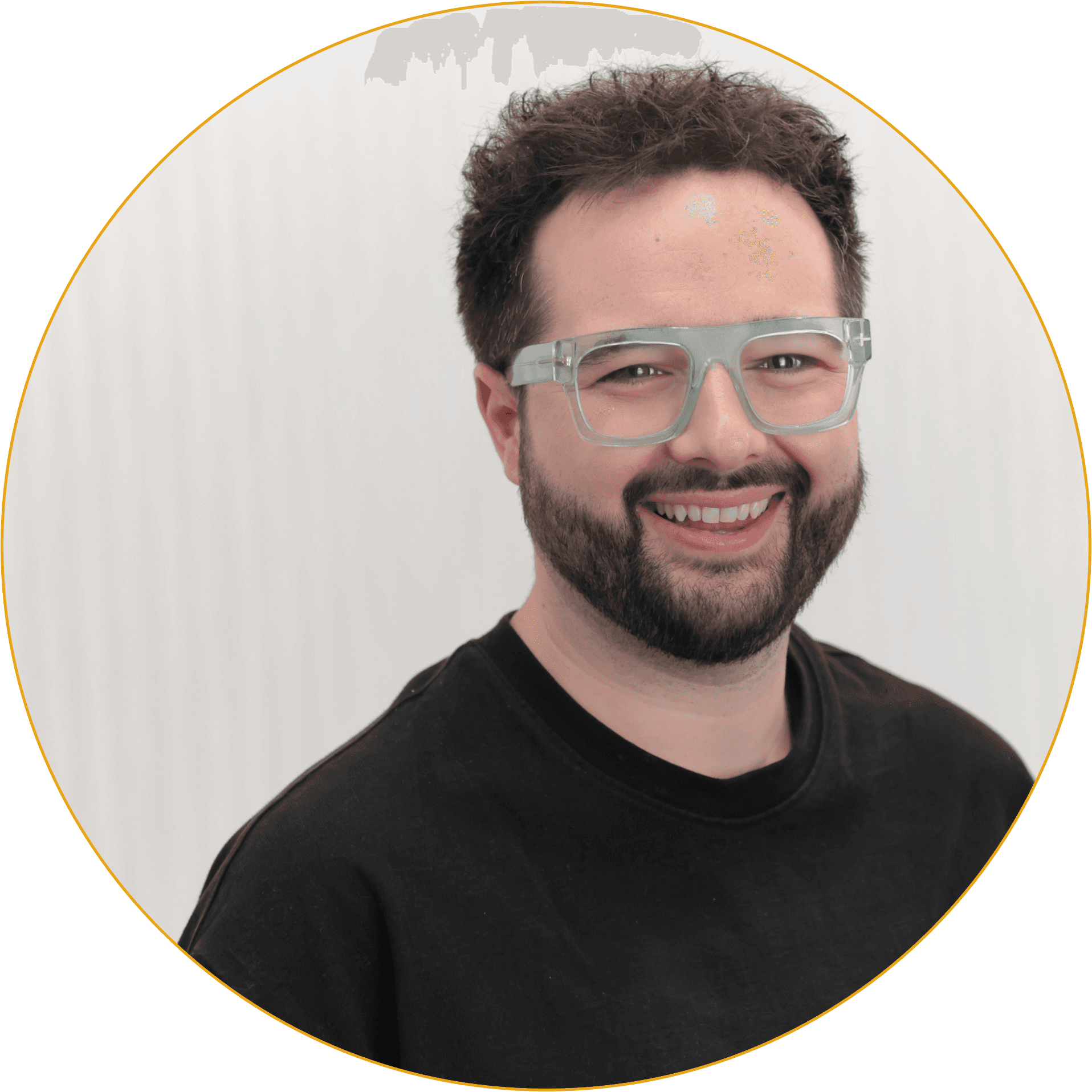 Headshot image of Scott Morgan, who has short dark hair & beard, wearing green glasses, and dark black top. Against a light background. 