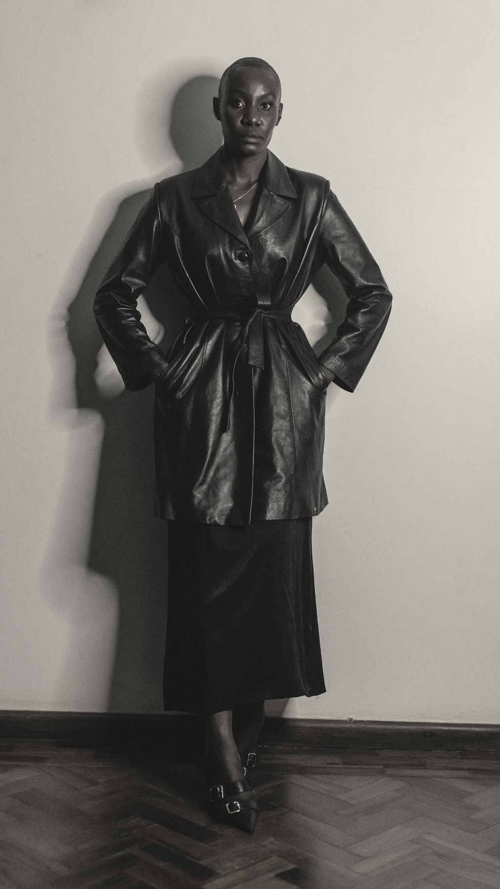 Model with hands on hips in a belted leather coat
