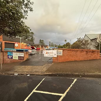 Hitech Remedial Group signage displayed on a brick fence at a Sydney construction or depot site on an overcast day