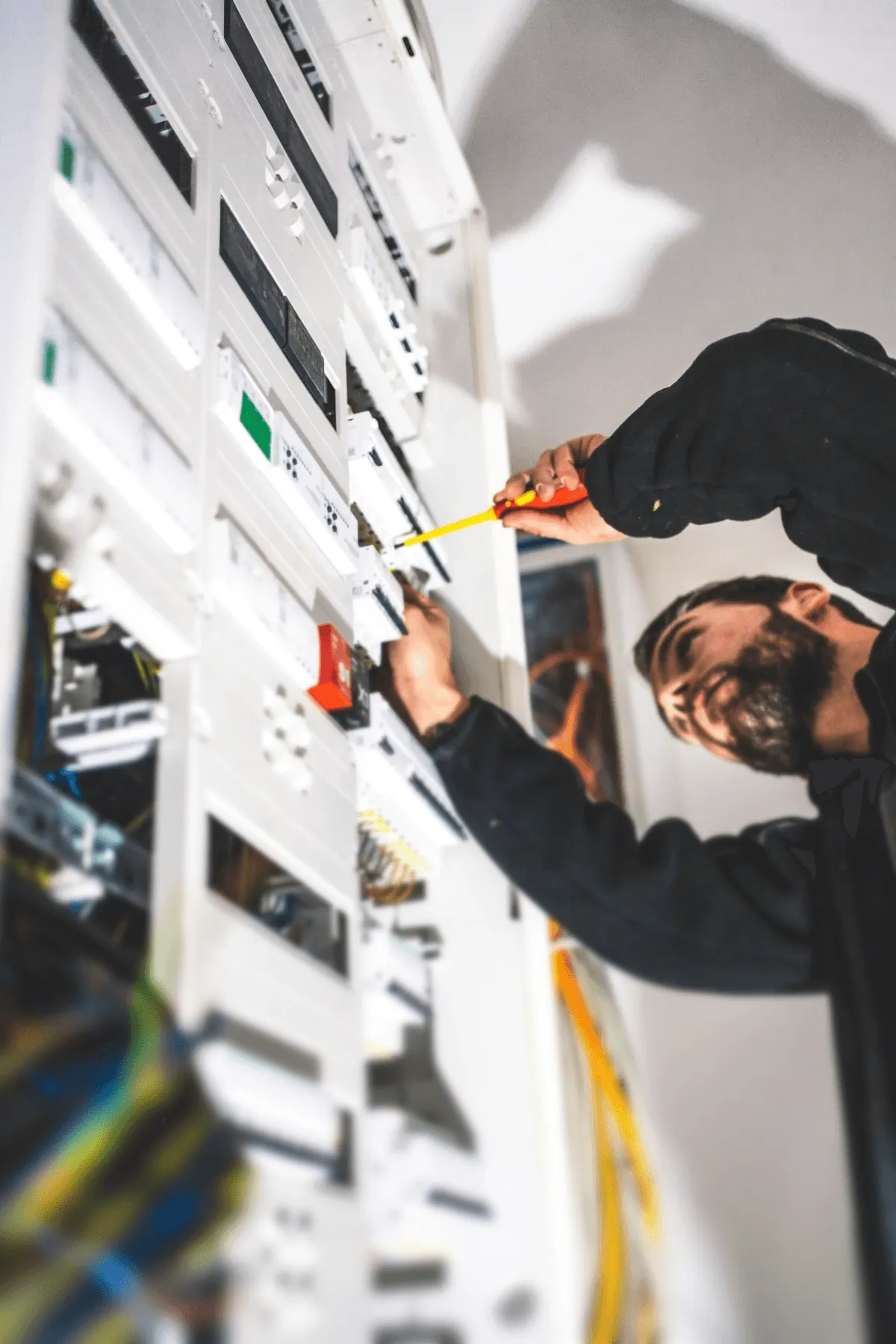 An electrician smiles gently while standing in front of control panels.