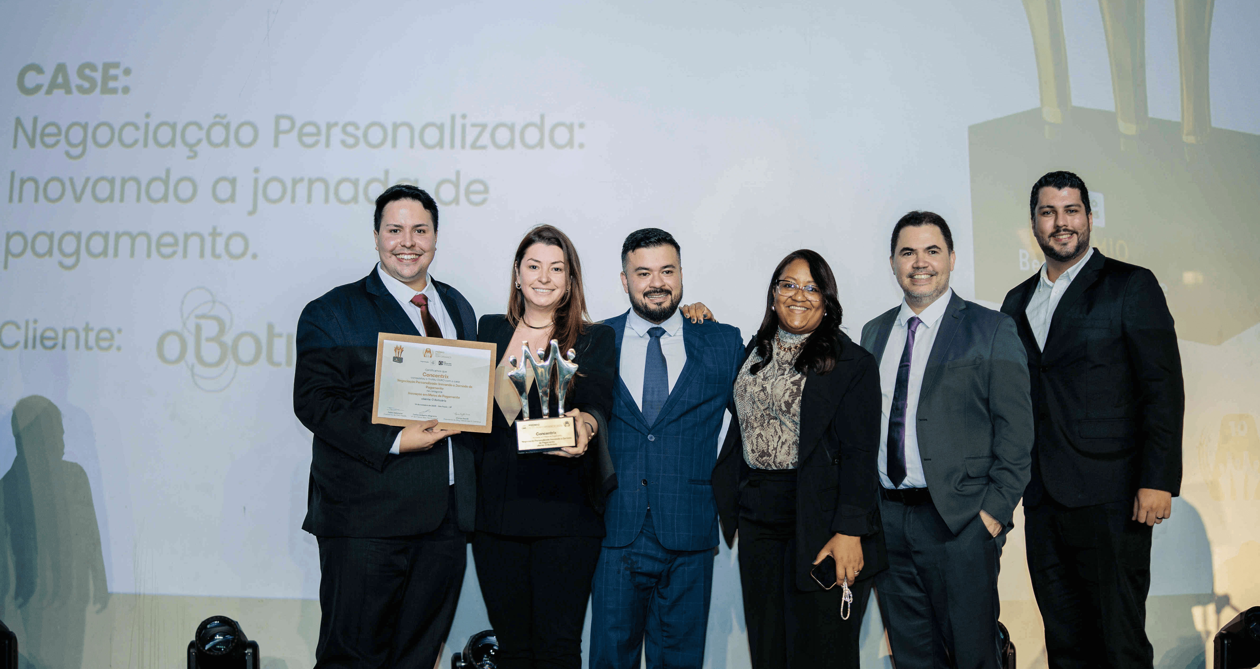 Executivos da Concentrix posando com troféu ouro e certificado no palco do Prêmio Best Performance 2025