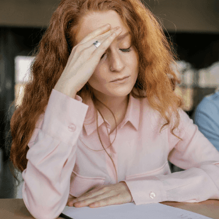 Stressed woman with hand on forehead, representing anxiety and the need for expert mental health support from HeadHealth.