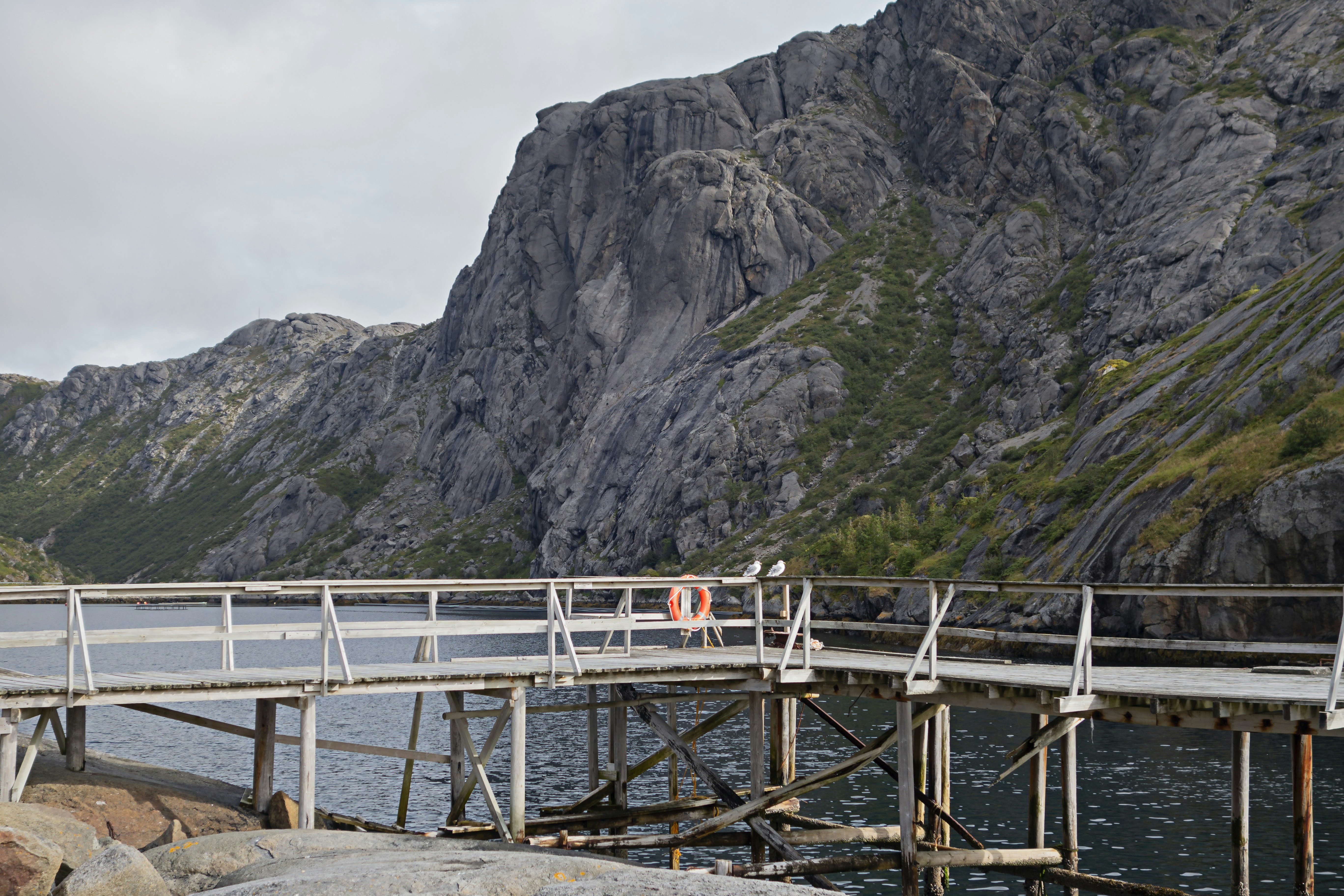 a wooden bridge over a body of water with mountains in the background