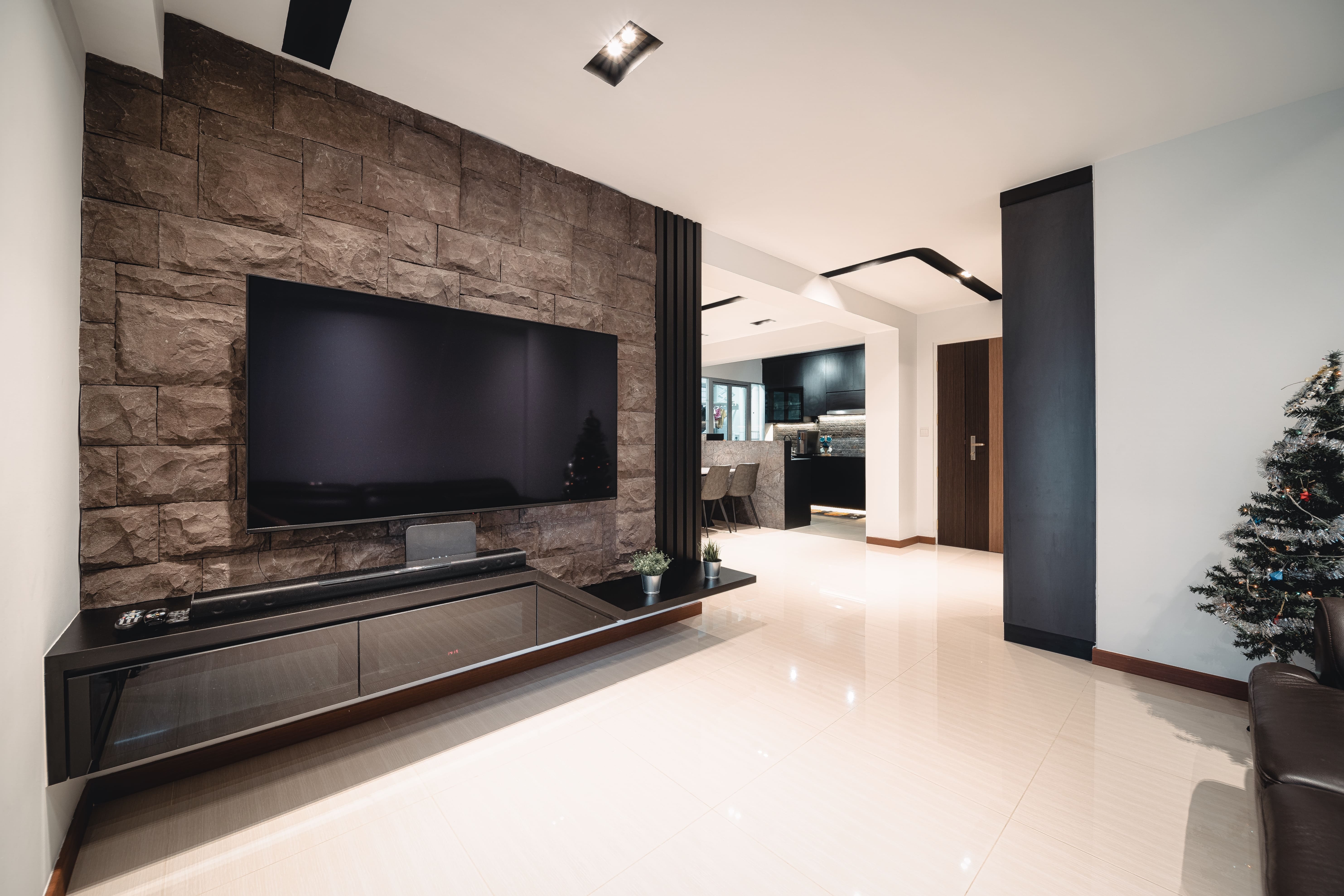 Living room with stone-clad TV feature wall and sleek entertainment unit, balancing raw texture with modern minimalism.