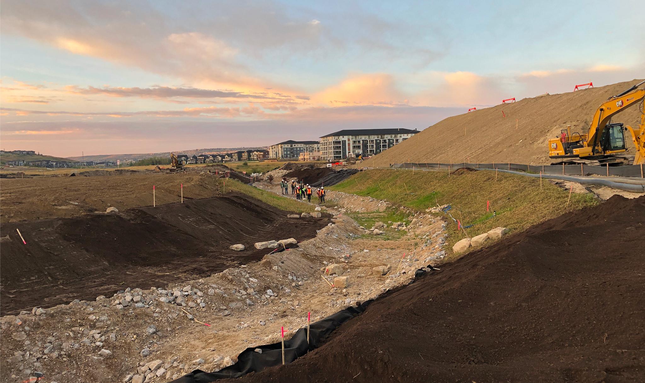 West Nose Creek channel realignment construction at sunset with crews preparing for channel activation sequence