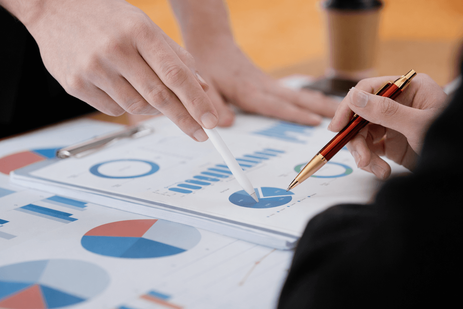 Group of four smiling colleagues standing indoors, wearing smart casual clothing.
