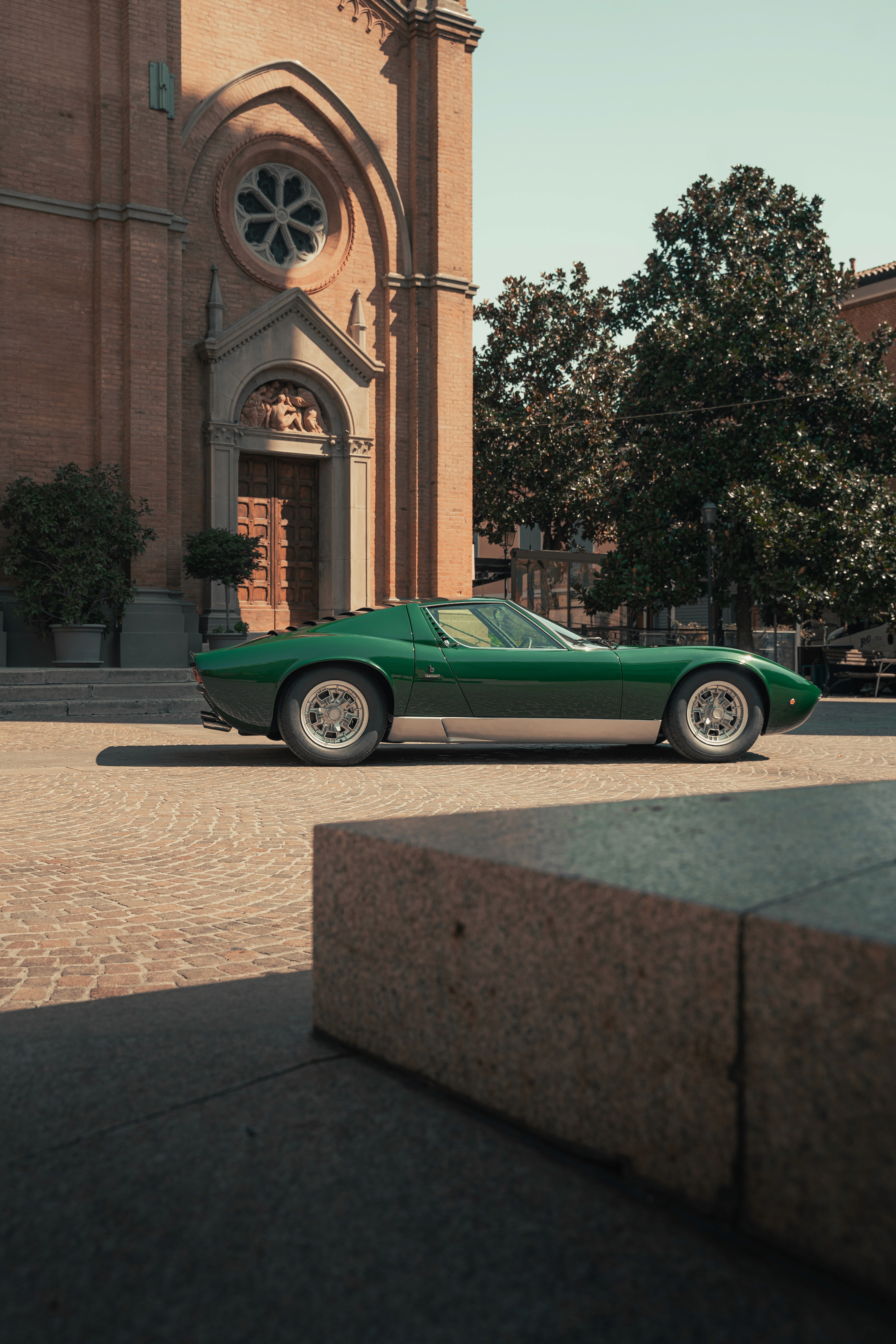 Rendering di suv elettrico BMW iX visto di tre quarti frontalmente, con carrozzeria blu ed interni in pelle in ambiente architettonico moderno.