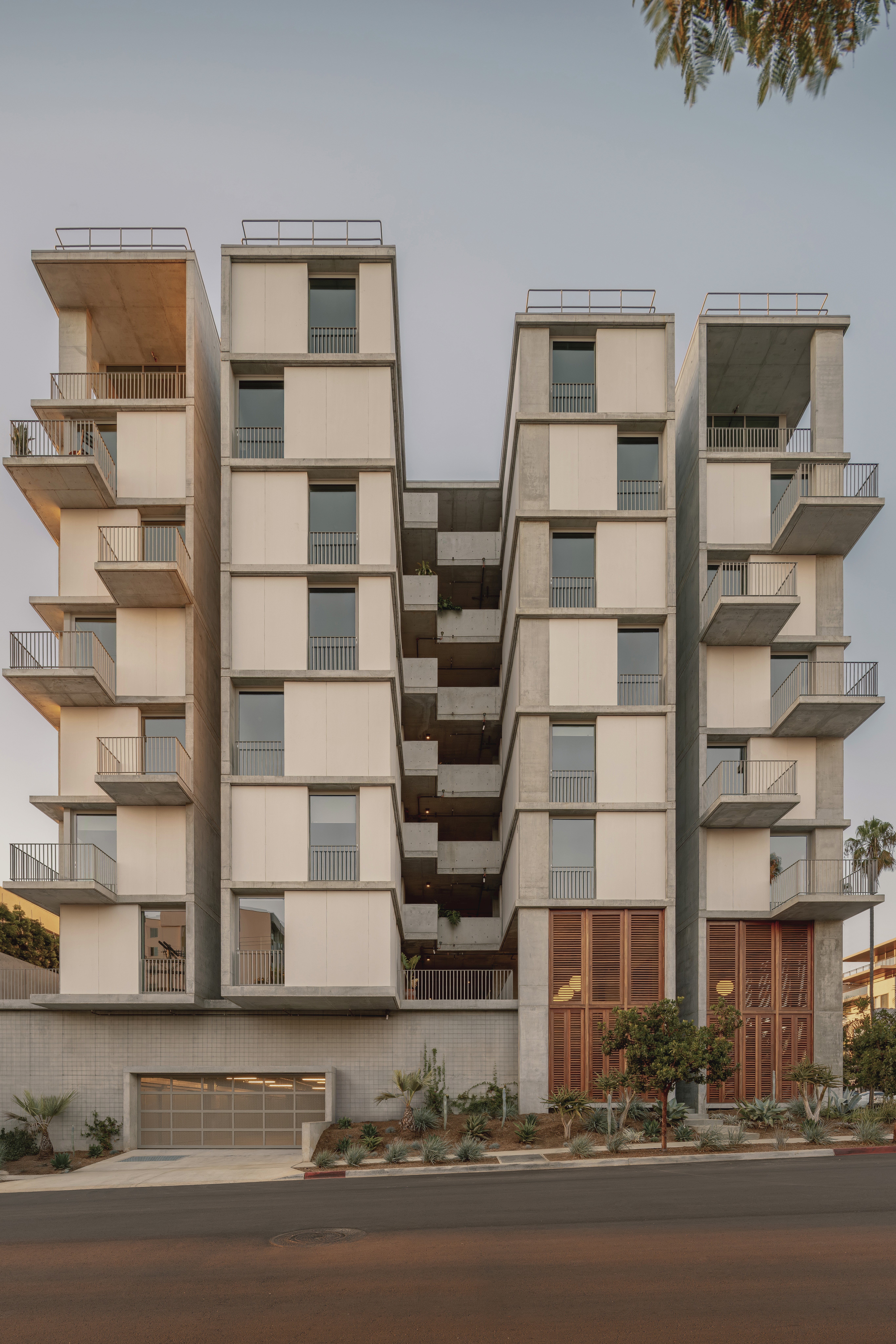 Modern apartment building with white, modular facade and large windows, set against a blue sky.